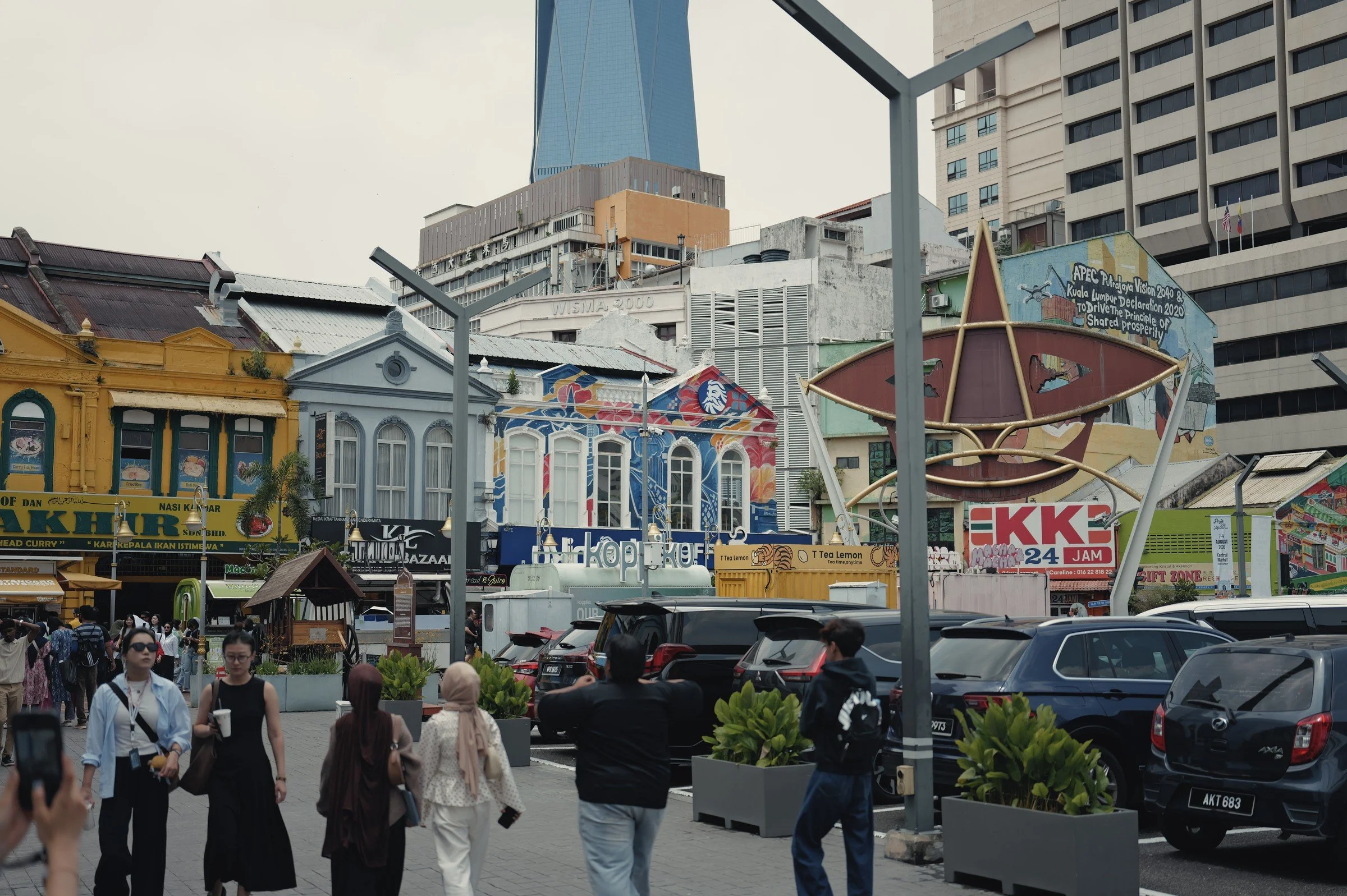 Colourful shophouses line a busy street beneath modern towers.