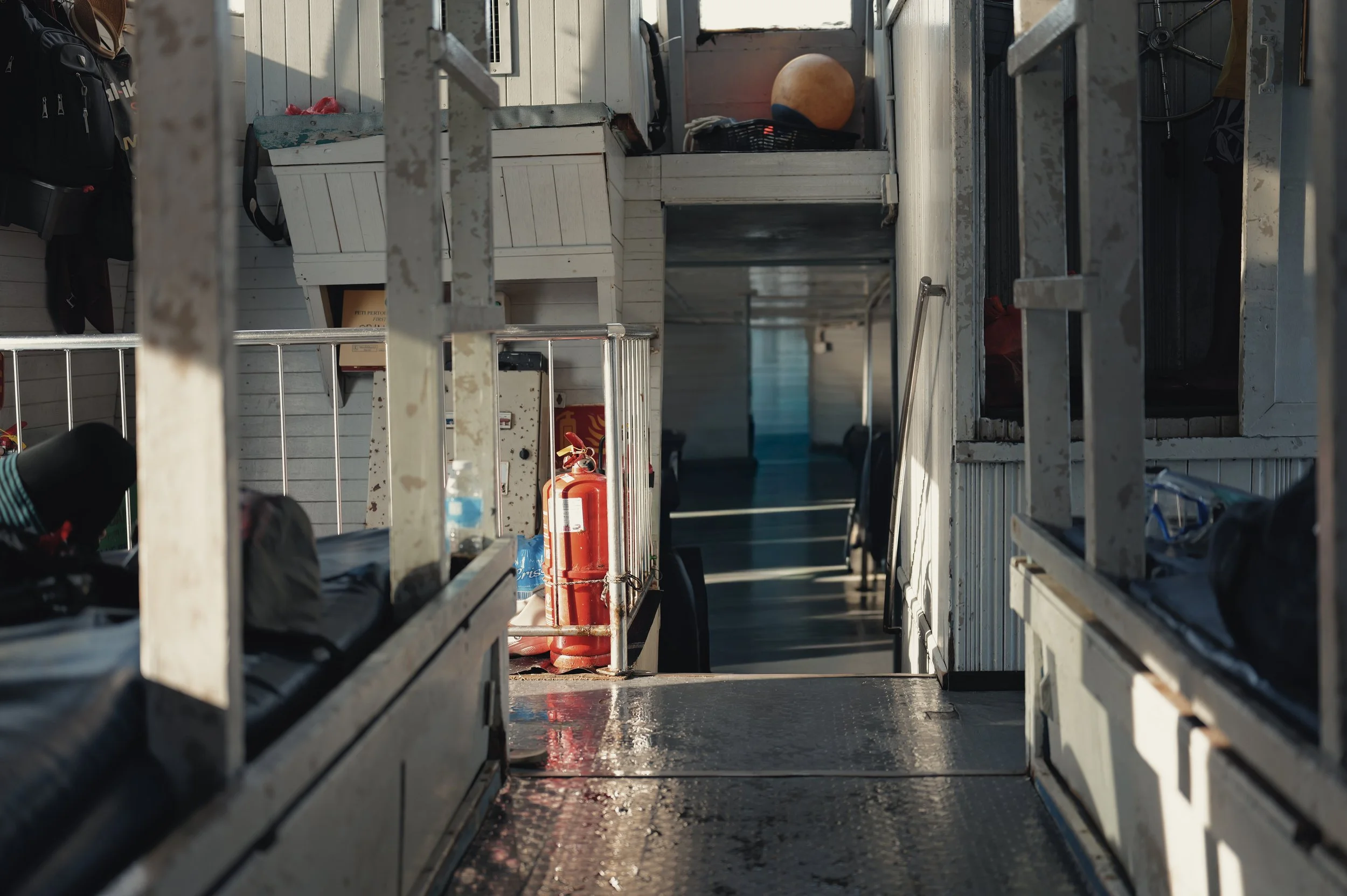 Photo of the interior of a truck or cargo vehicle with various items including a fire extinguisher and a ball, taken from a low angle looking towards the back of the vehicle.