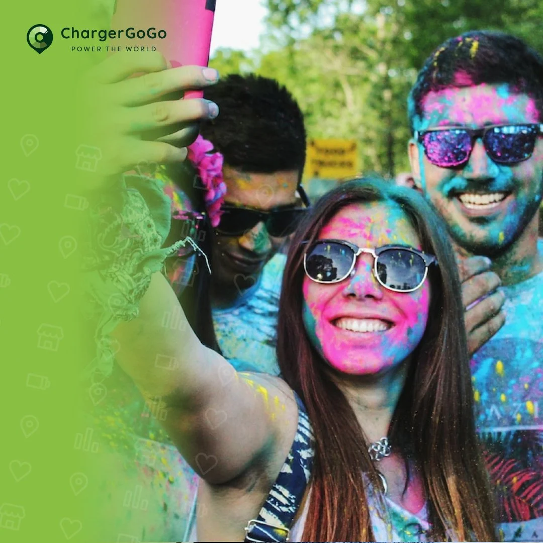 Group of friends celebrating at a color run event covered in colorful powder, smiling for a selfie.
