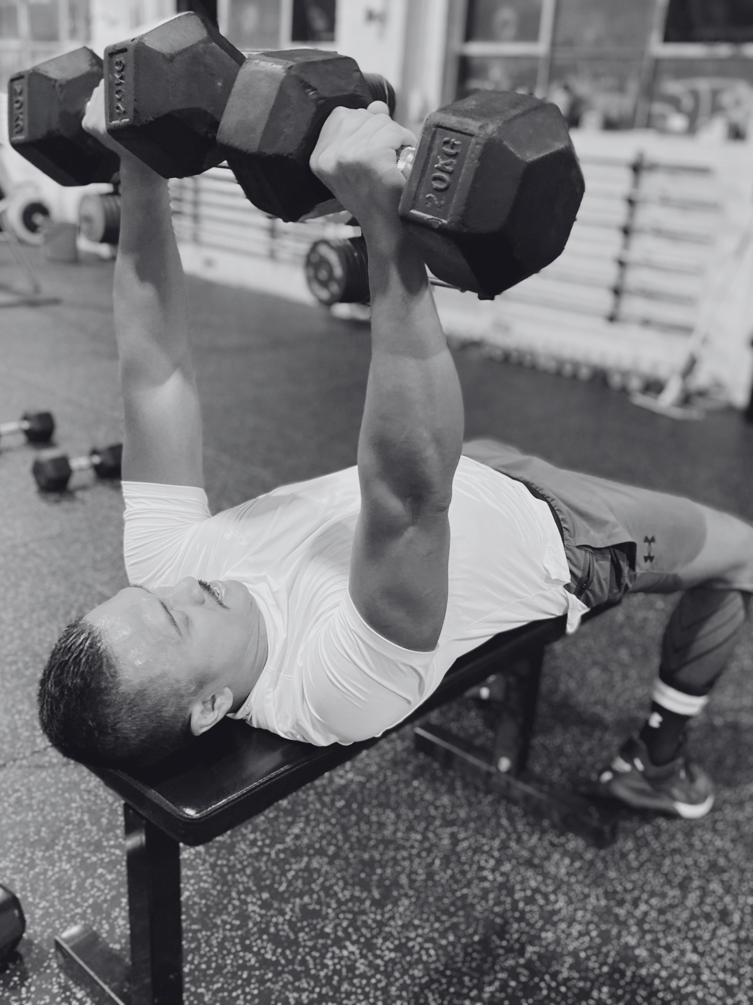 Asian man completing dumbbell bench press inside stance training