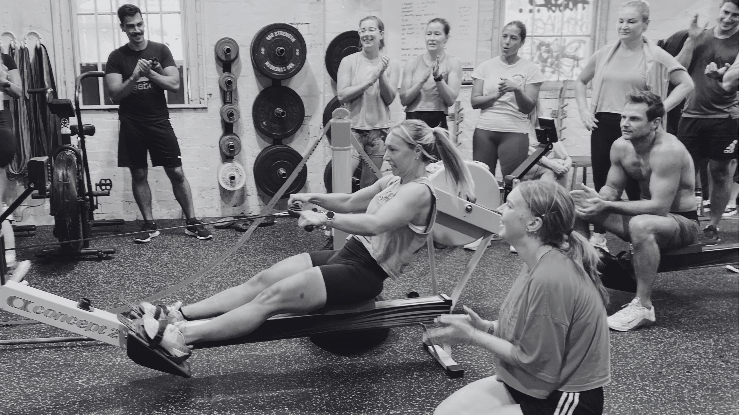 Group of athletes encourage  a woman rowing in her final meters.