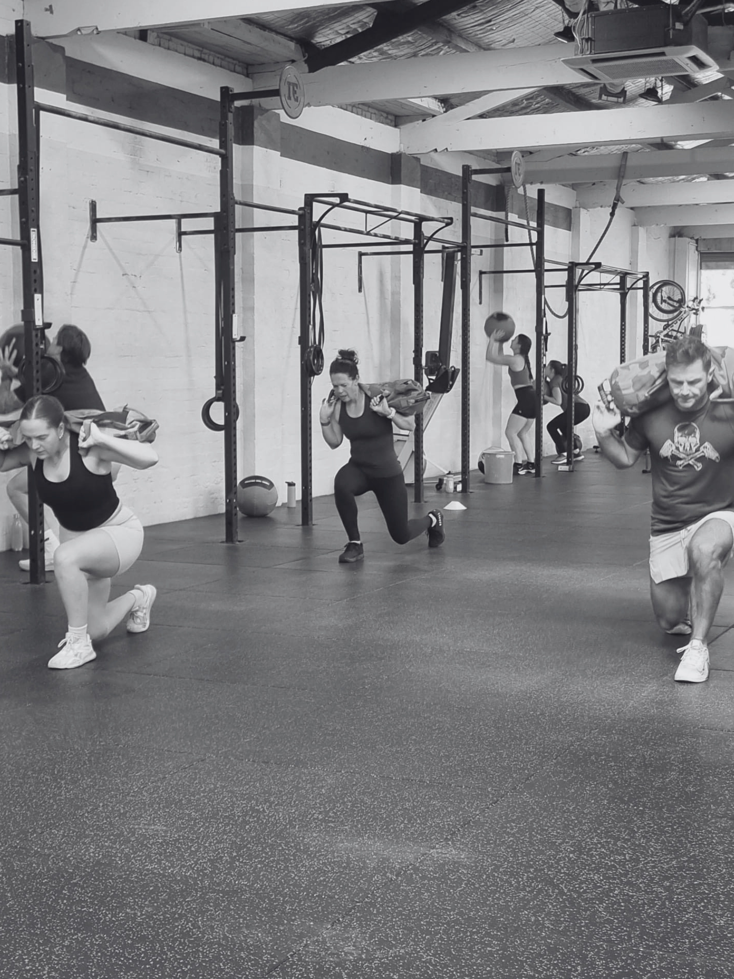 Hyrox race prep inside Stance Training completing sandbag lunge