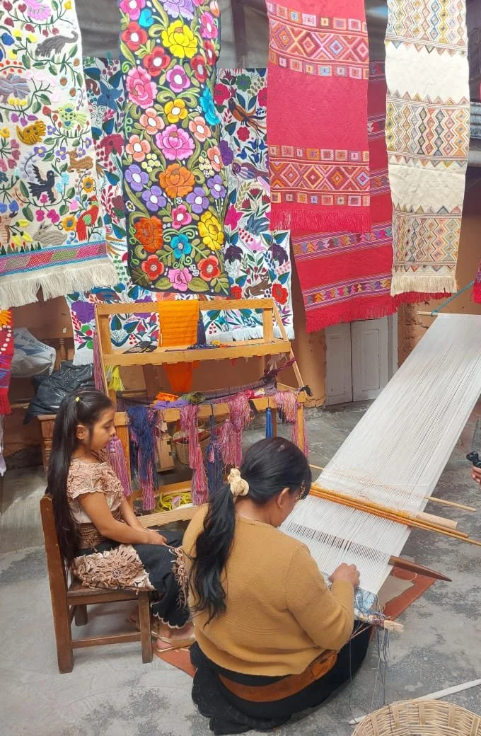 A modern day Tzotzil Mayan woman working on the traditional backstrap loom or Telar de Cintura with her daughter watching