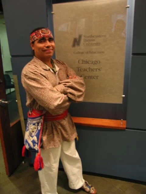 Maestro Ocelocoatl after giving a multimedia presentation standing next to a sign for the Chicago Teachers Center at Northeastern Illinois University.