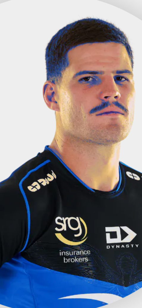 A man wearing a sports jersey with sponsor logos, including sig insurance brokers and Dynasty, posing against a plain background.