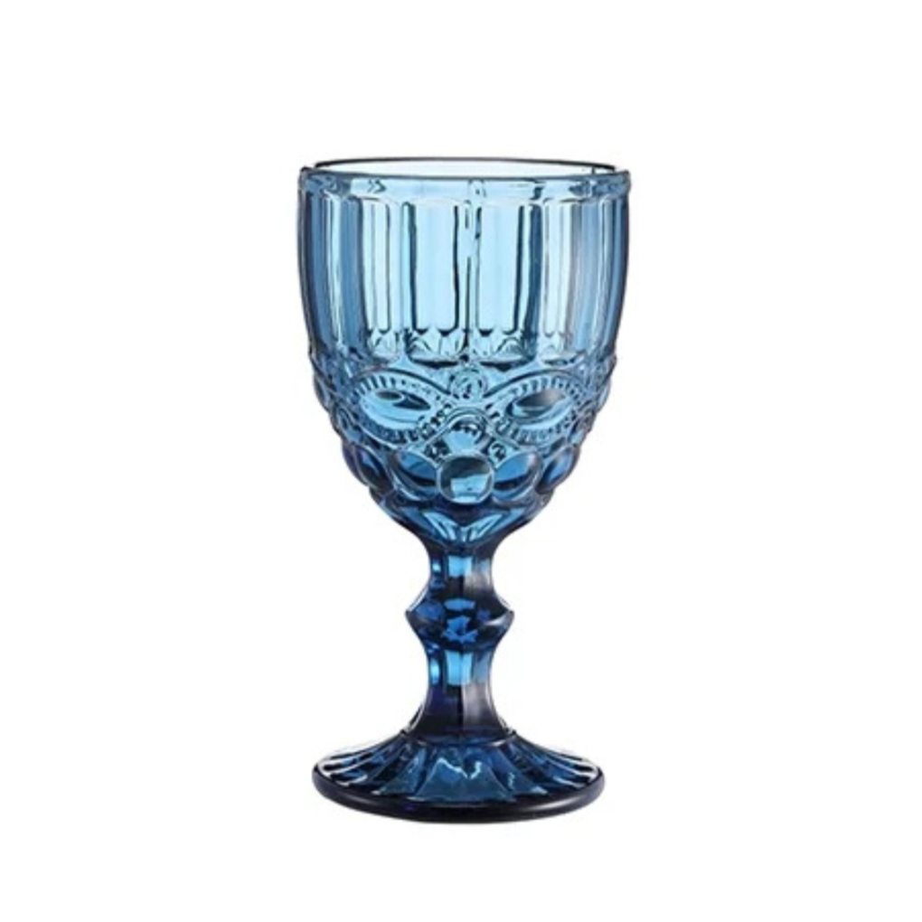 Blue glass goblet with an ornate design resembling a tiki face, on a white background.
