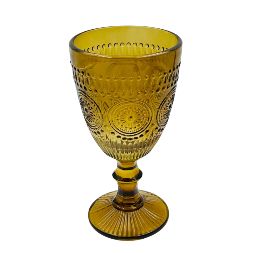 A decorative yellow glass goblet with intricate embossed patterns, set against a plain white background.