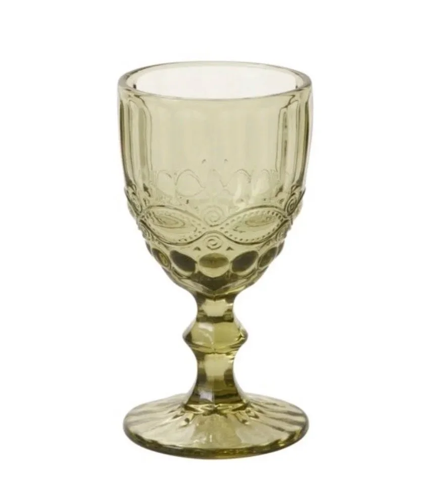 A clear, decorative glass goblet with intricate patterns and a slightly tinted green hue.