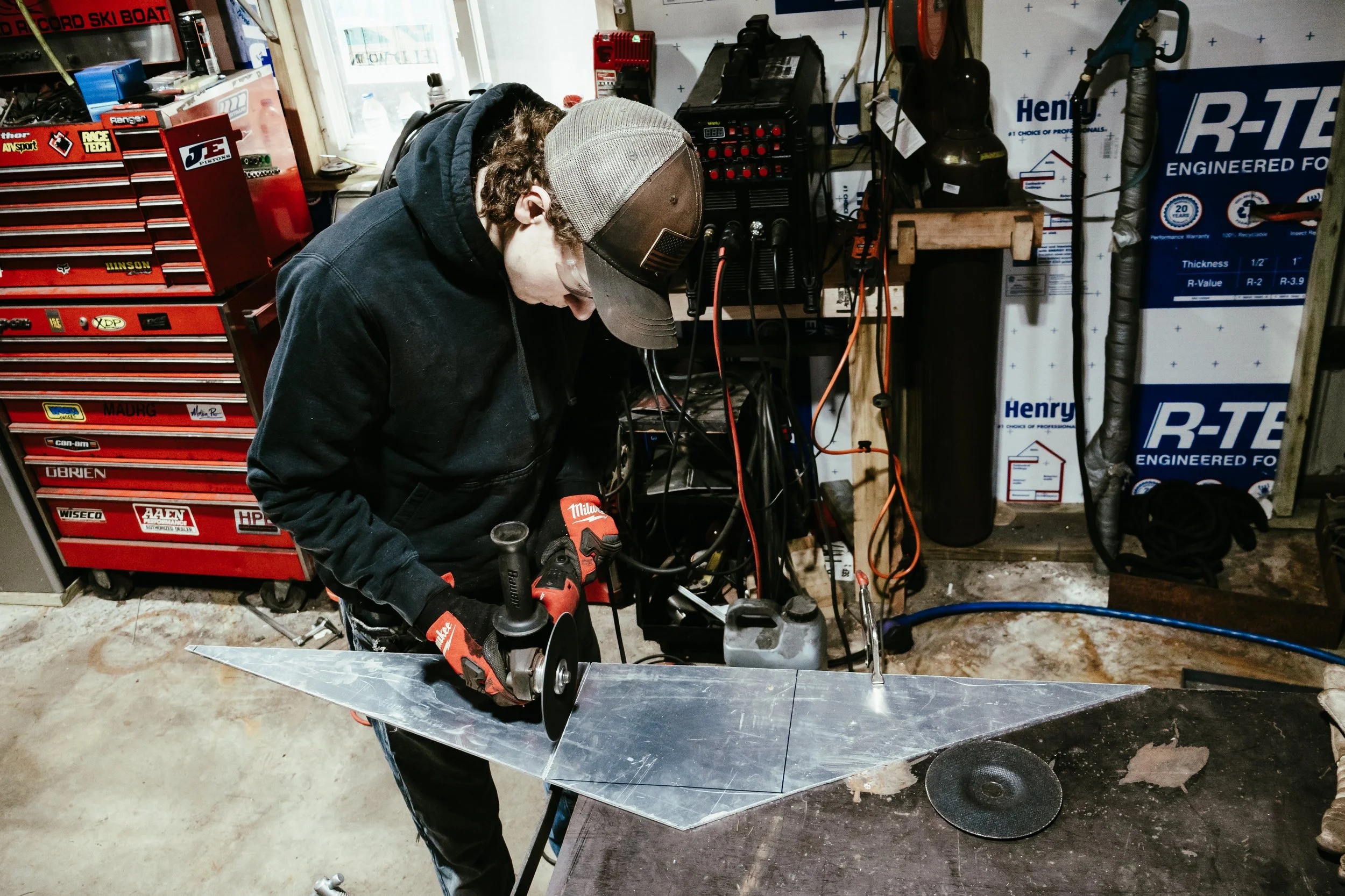 Person working on a metal project in a garage workshop, with tools and equipment around.