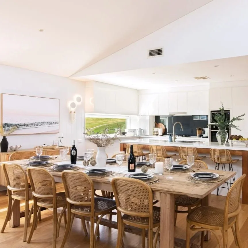 Open-plan kitchen and dining with rattan chairs and marble countertop styled by Terra Styling — South Coast NSW