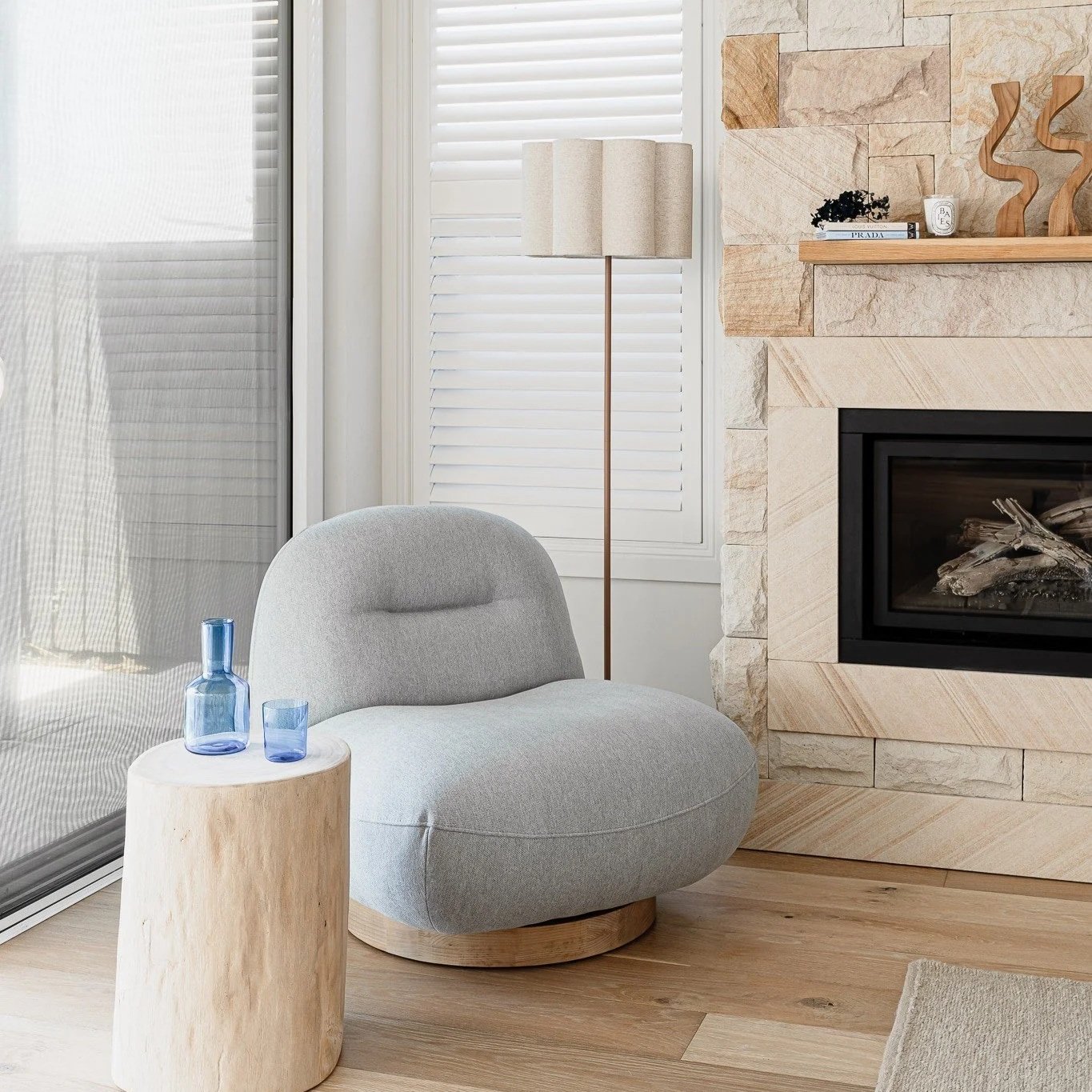 Reading corner with armchair, side table, and stone fireplace styled by Terra Styling — Barrack Point