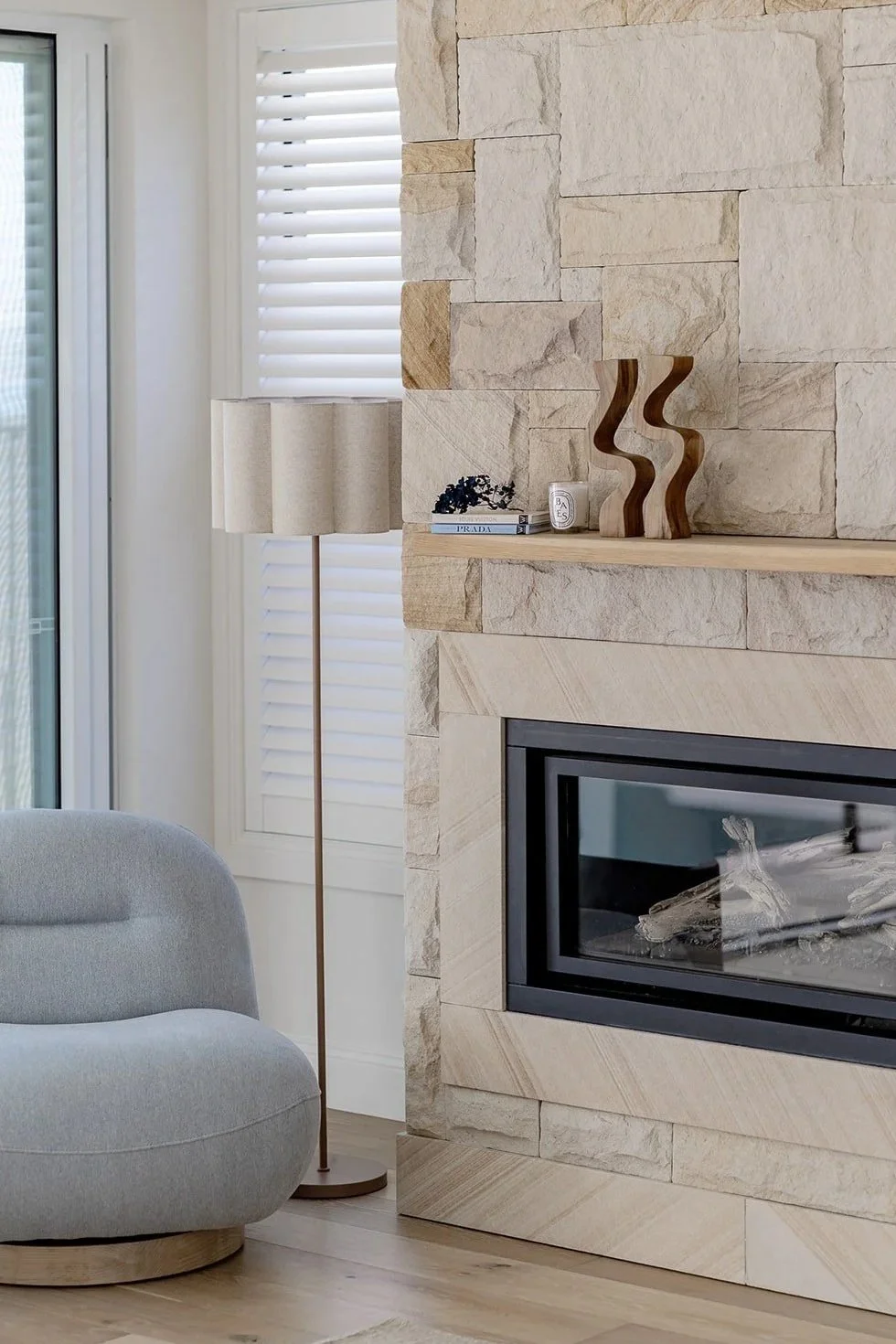 Stone fireplace detail with armchair and floor lamp styled by Terra Styling — South Coast NSW
