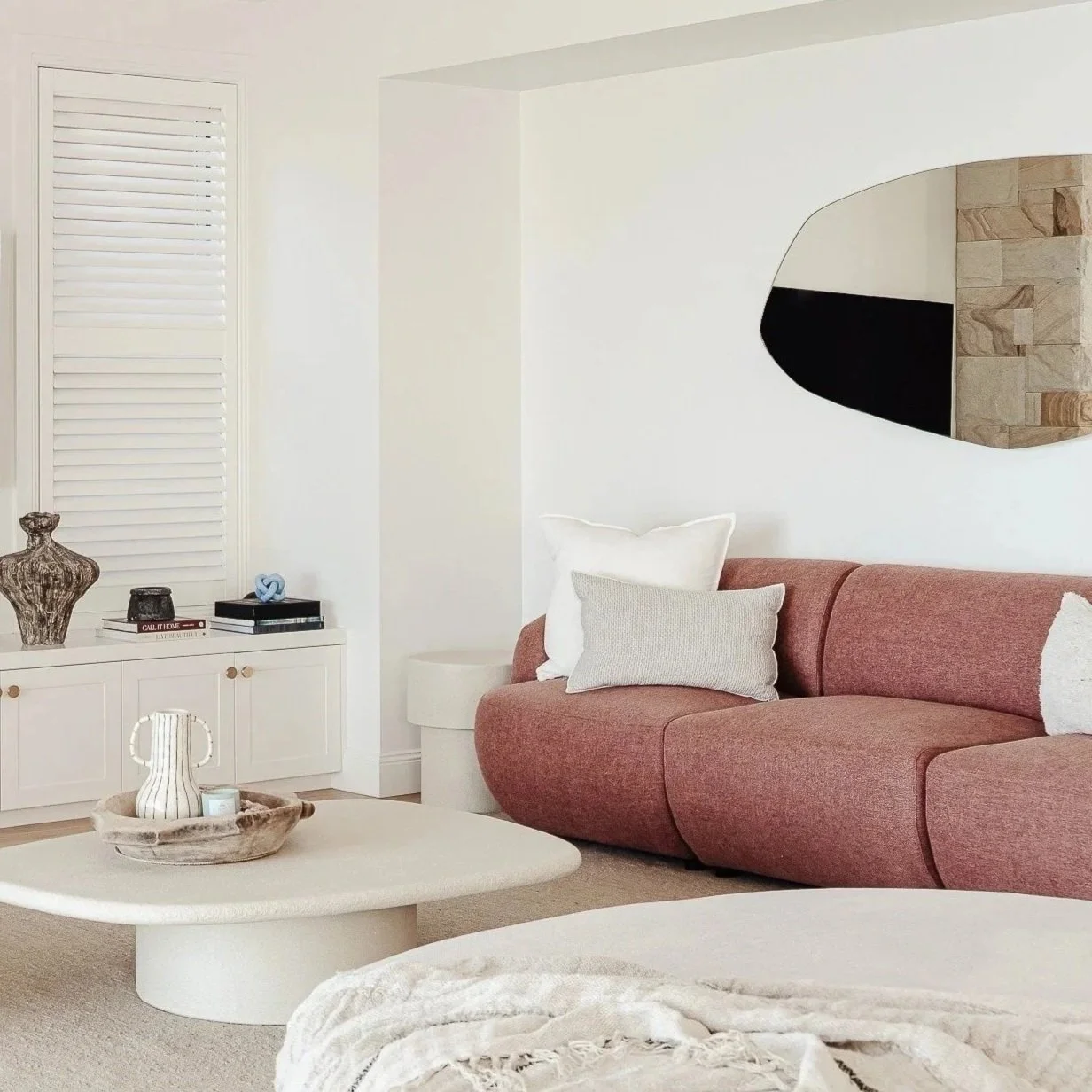 Living room with pink sofa, white coffee table, and organic mirror styled by Terra Styling — Barrack Point