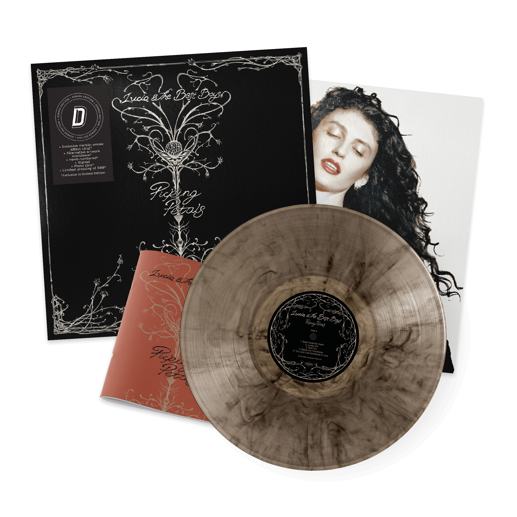 Vinyl record with a marbled brown and beige appearance, album cover with a black background and white intricate floral design, image of a woman with curly black hair and red lipstick, and a booklet with matching design elements.