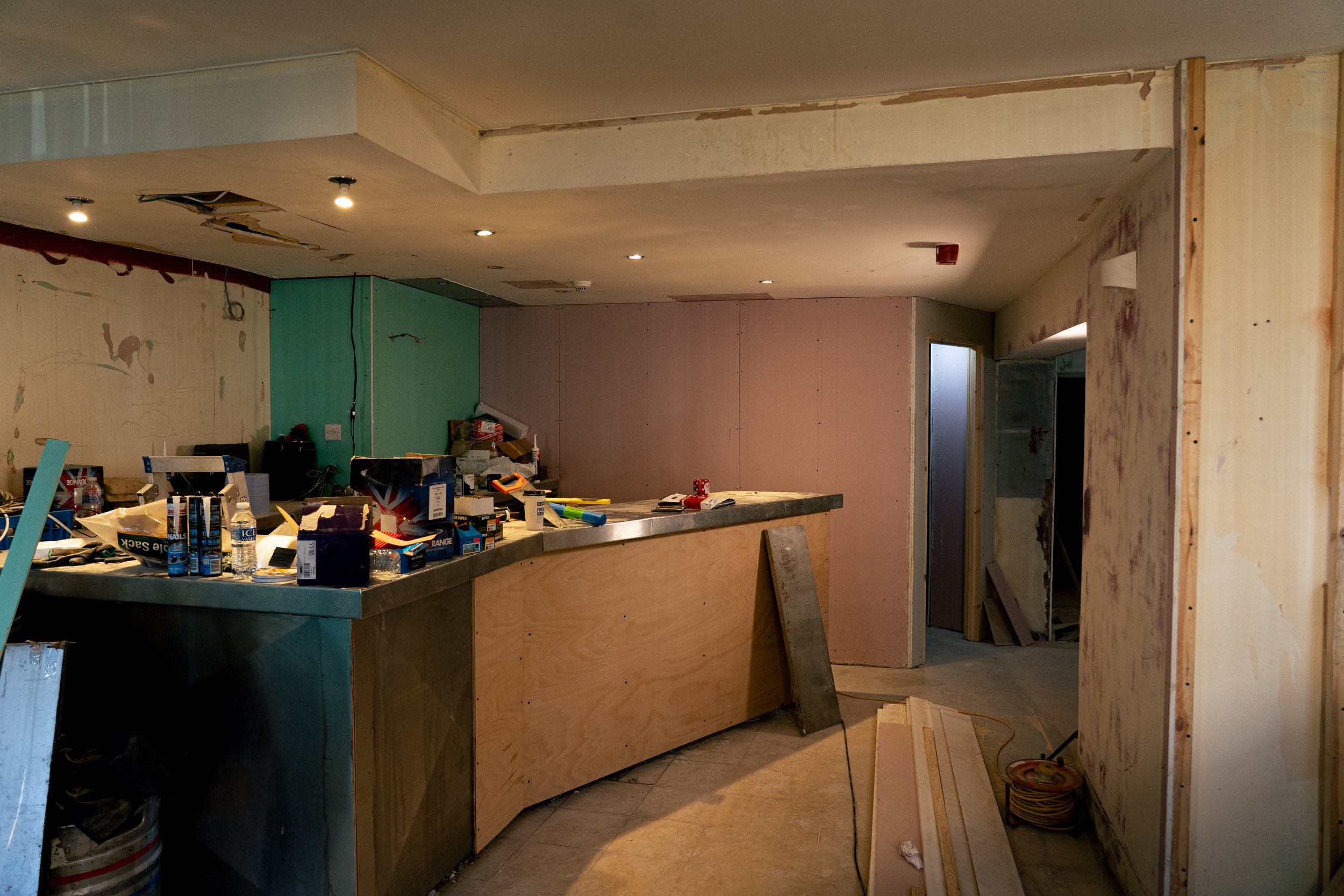 Interior of a building under renovation, with construction tools, supplies, and unfinished walls.