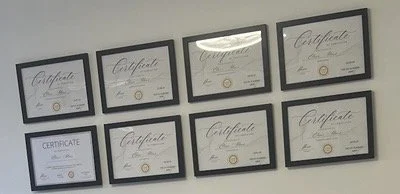 A wall with eight framed certificates arranged in two rows of four.