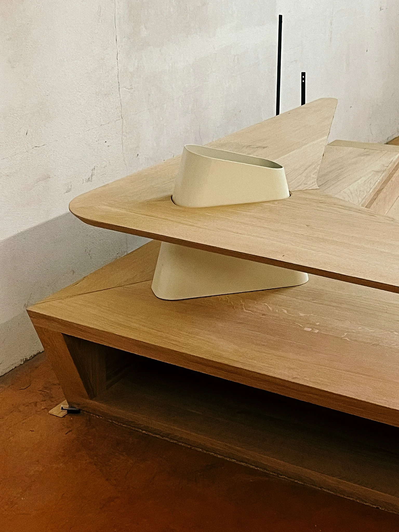 Une sculpture moderne en forme de bateau, faite de différentes pièces de bois de couleurs et formes variées, posée sur une table en bois.