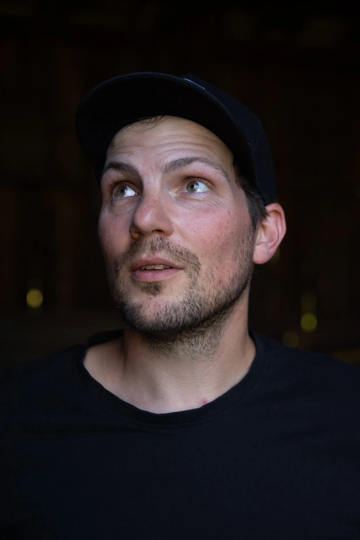 Porträt zeigt den Winzer Arnold Holzer, er trägt eine schwarze Kappe und ein schwarzes T-Shirt, blickt nach oben.