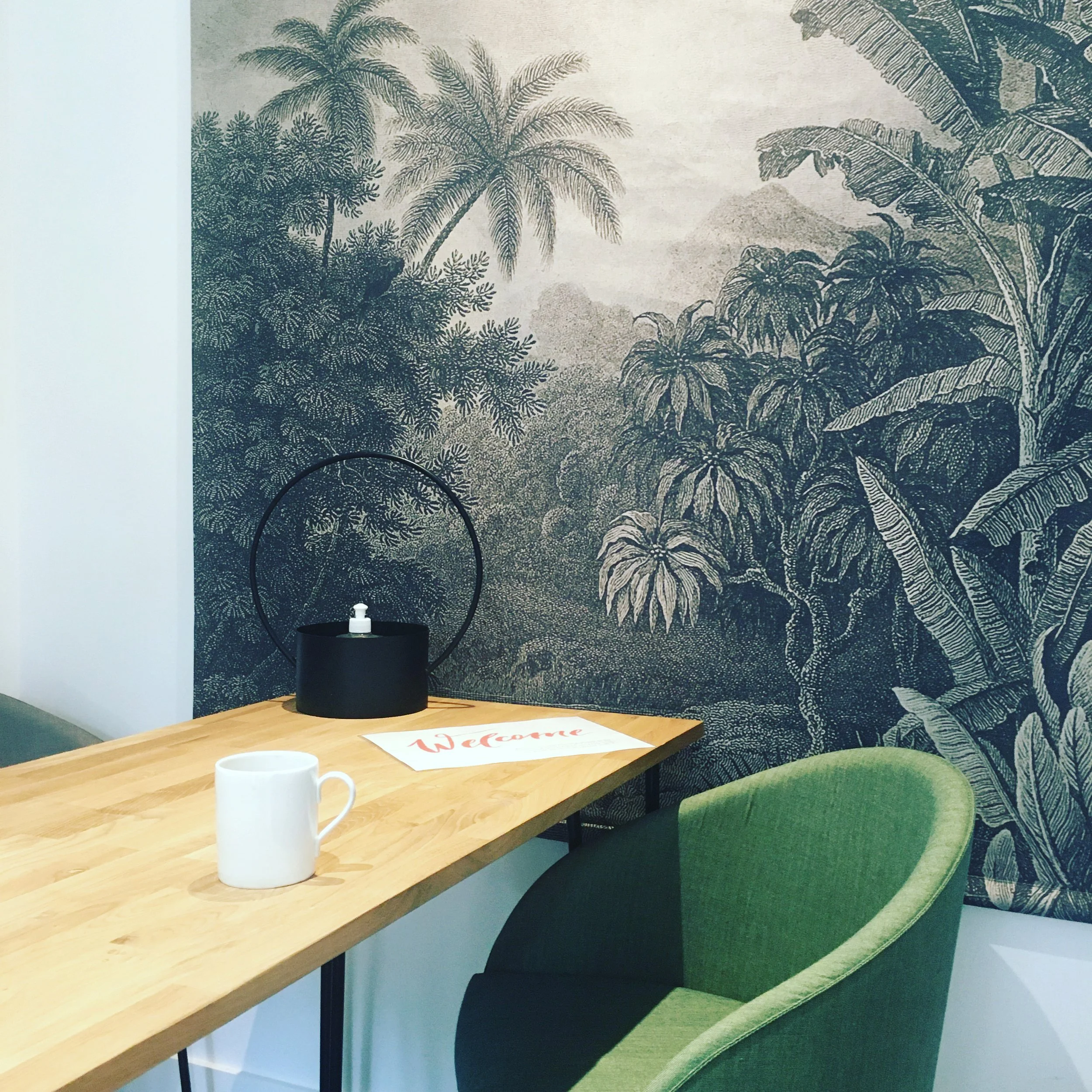 Une table en bois avec deux tasses blanches et un tapis 'Welcome' rouge et blanc.