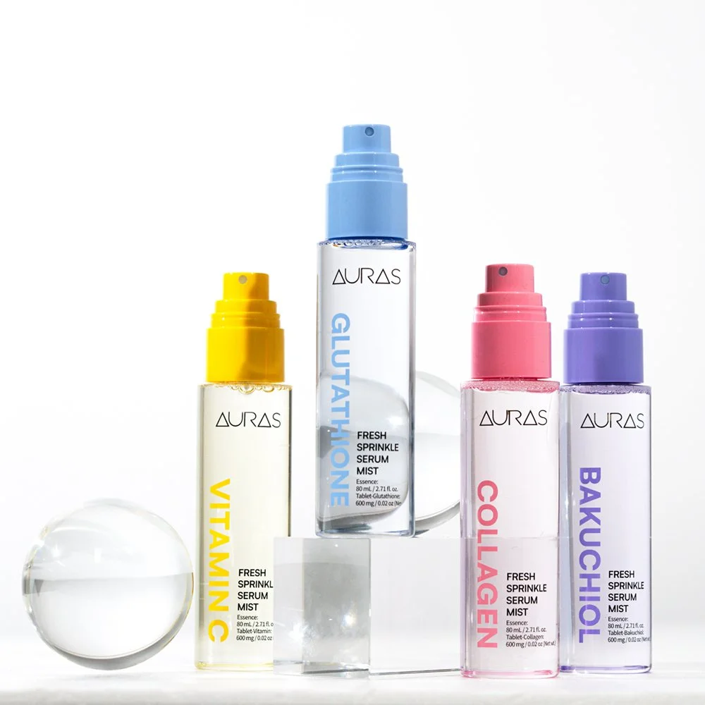 Collection of four skincare serum bottles with colorful spray caps labeled Vitamin C, Glutathione, Collagen, and Bakuchiol, set against a white background on a clear acrylic stand.