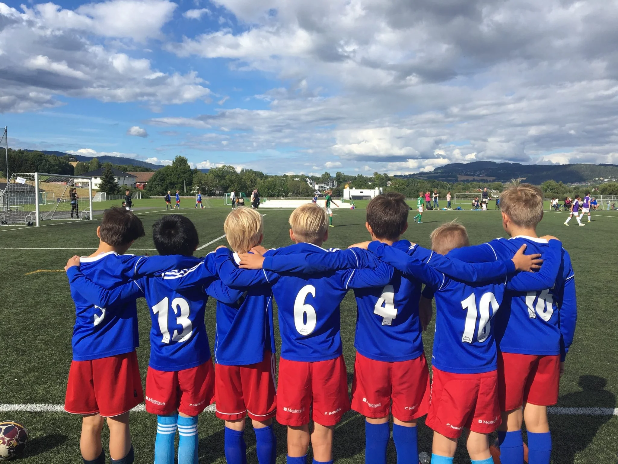 7 barn i SpaBra-drakt med ryggen til på fotballbanen