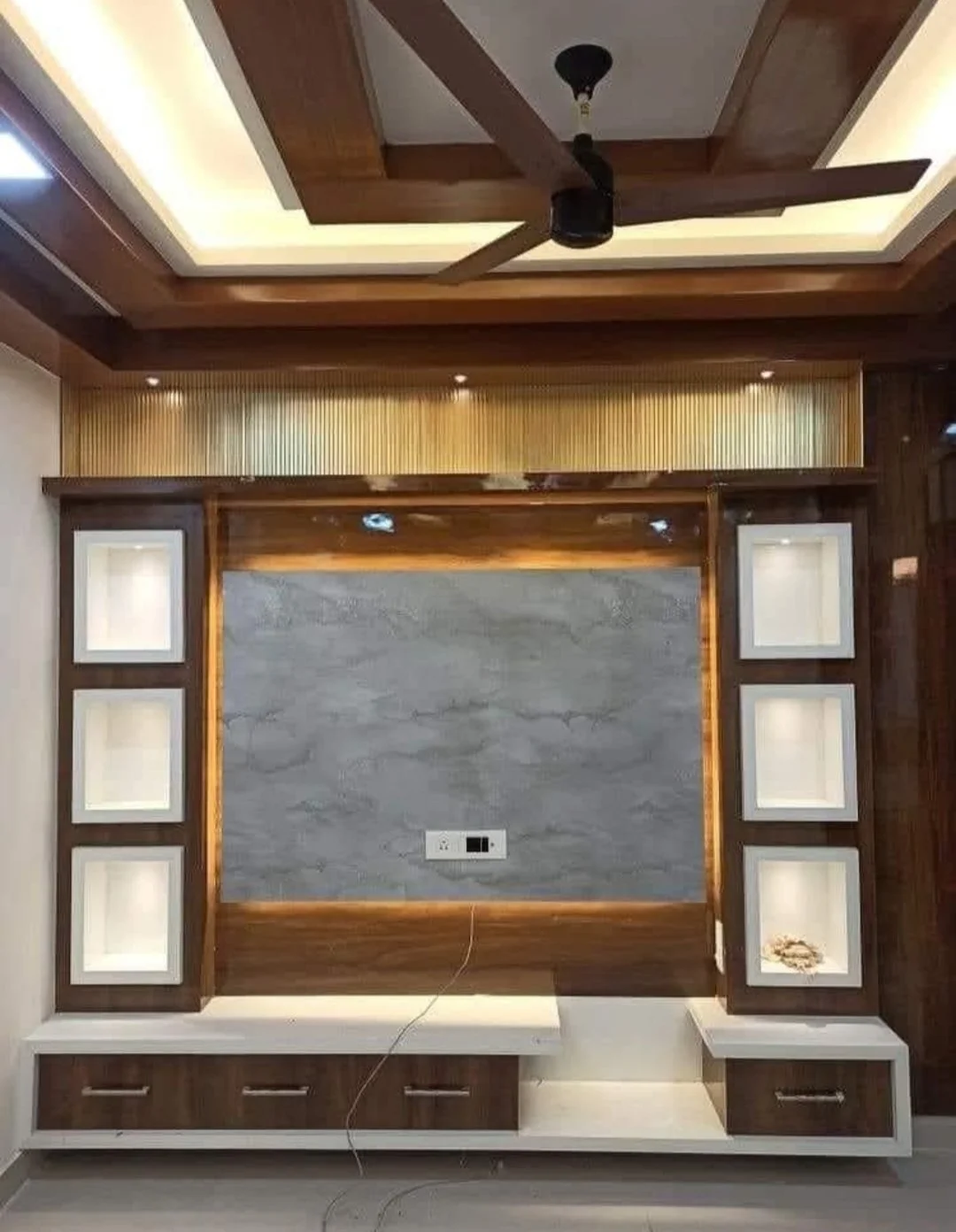 Modern TV unit design with poly granite sheet wall panelling in Sri Ganesh Township, Ballepalli.