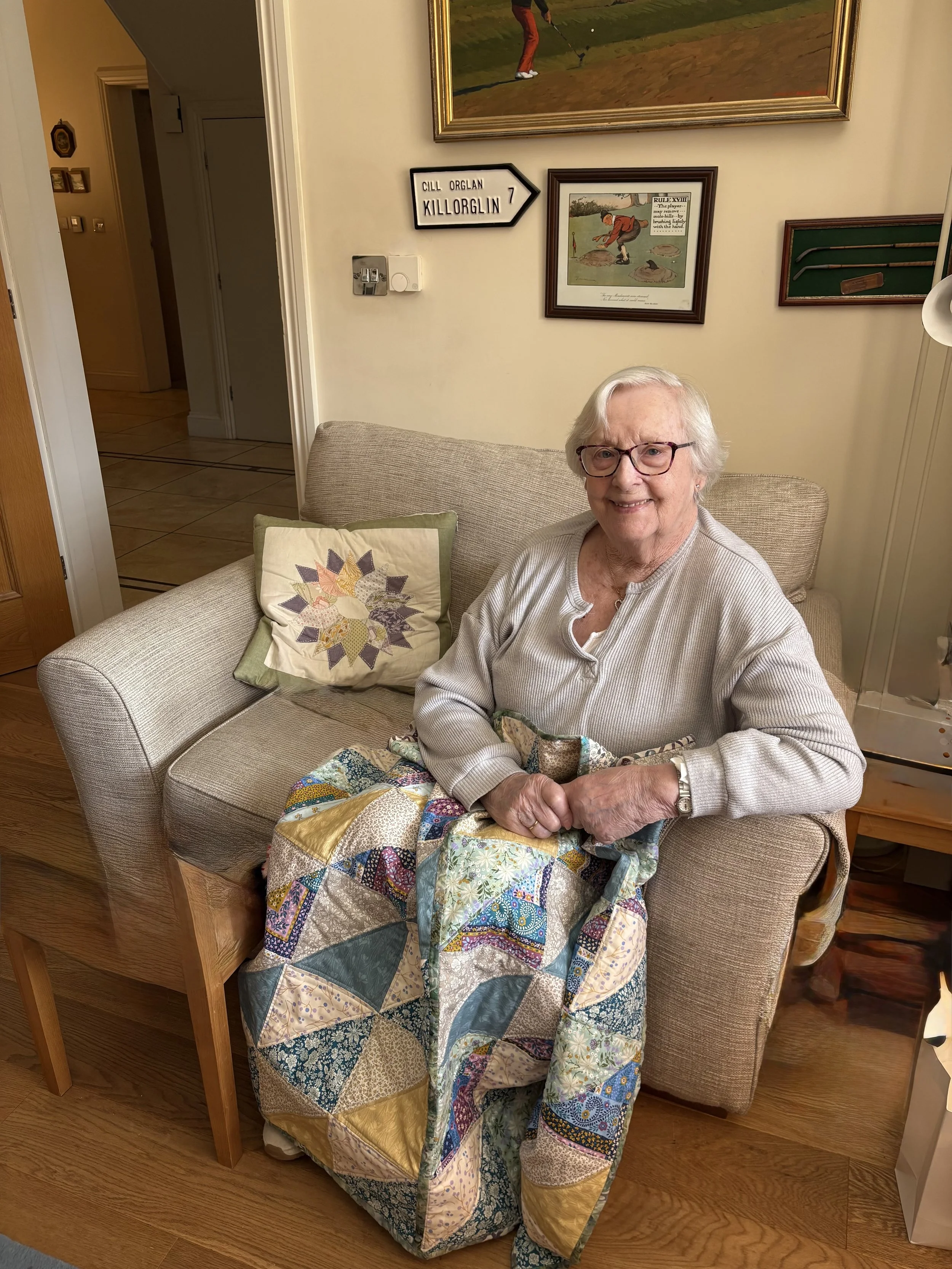Handmade patchwork lap quilt shown in use on a chair, an example of a Brighton Stitch memory quilt commission