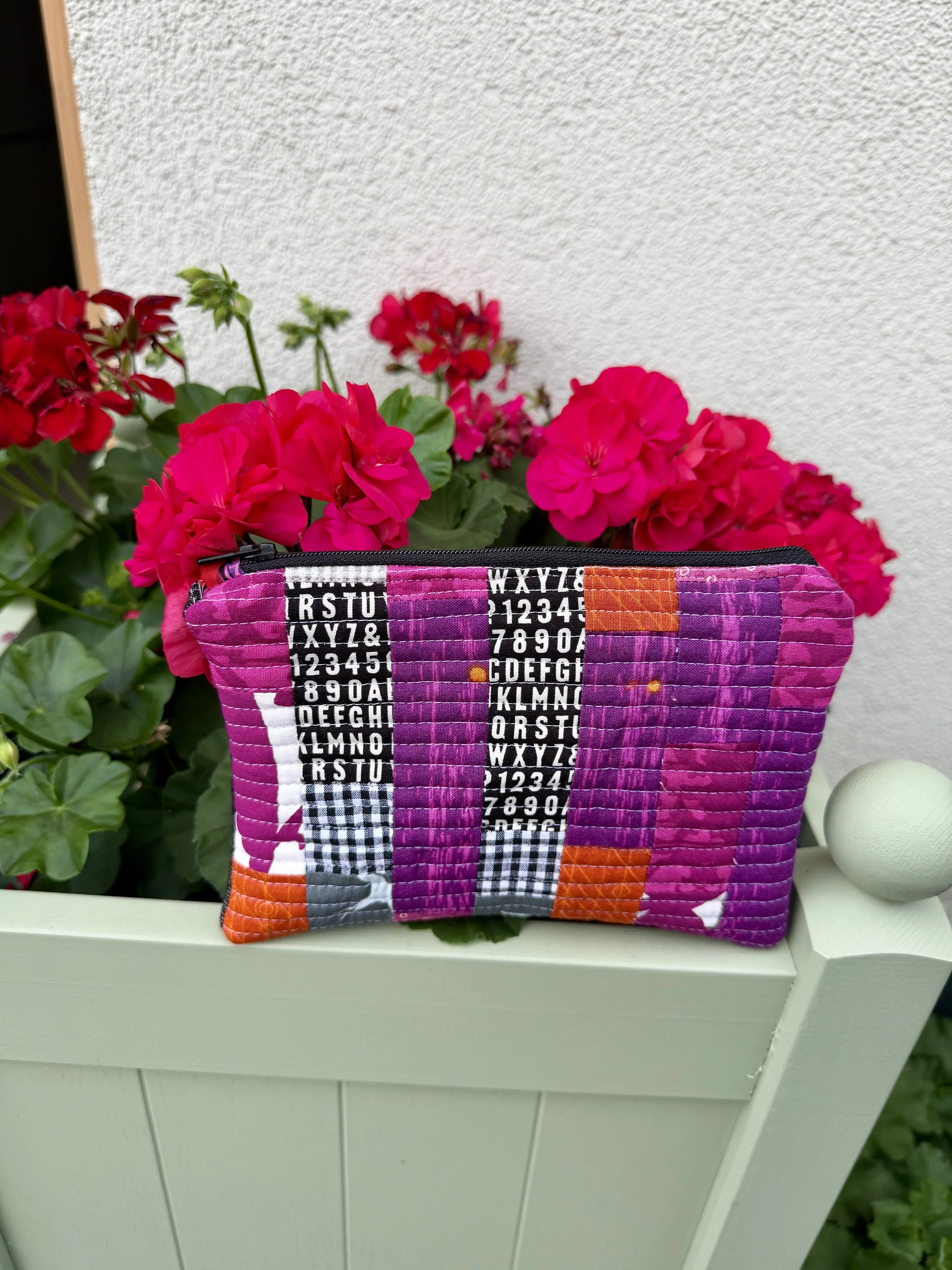 handmade patchwork pouch photographed amongst geraniums