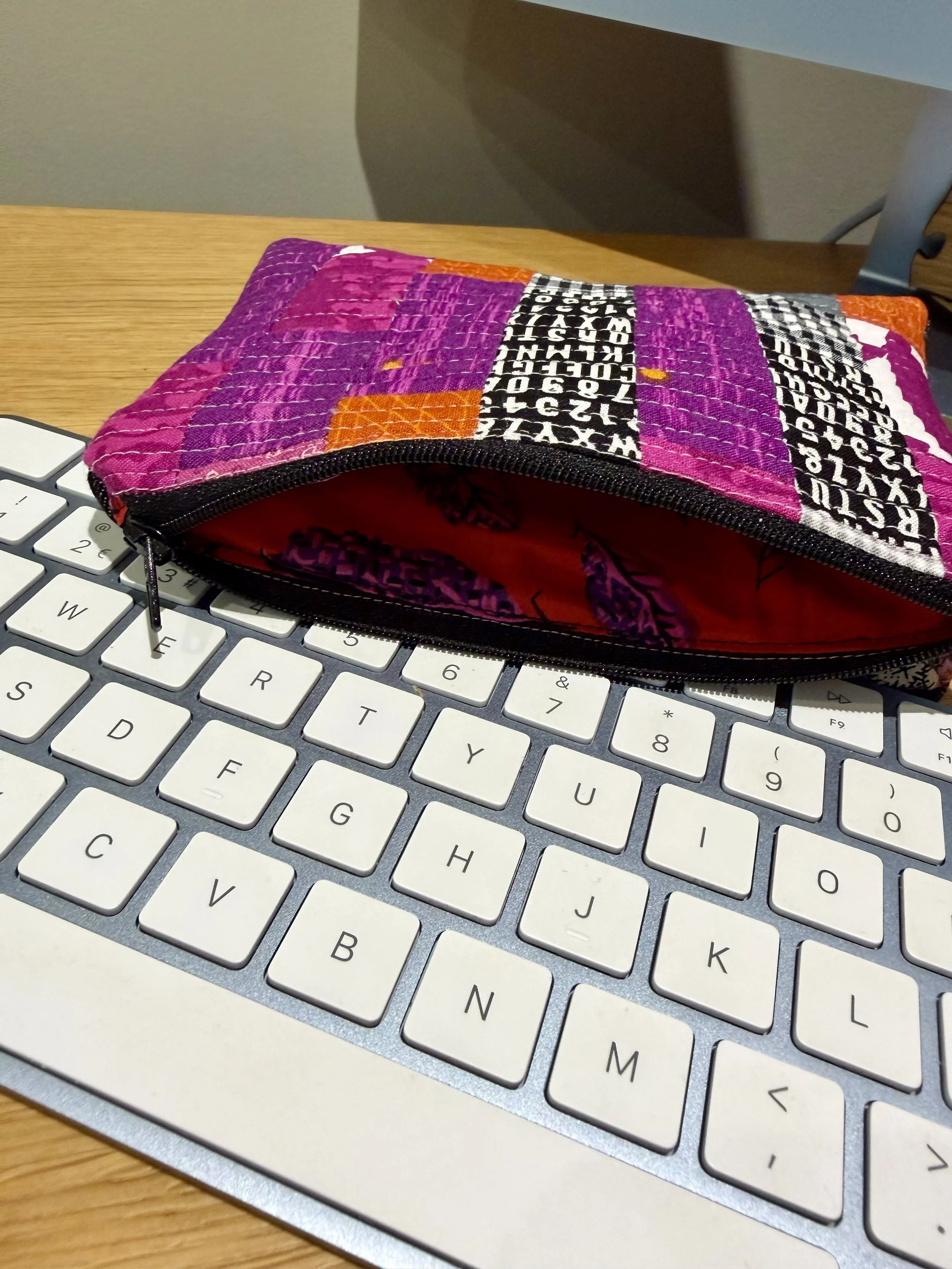 Open patchwork pouch on keyboard showing colourful patterned cotton lining