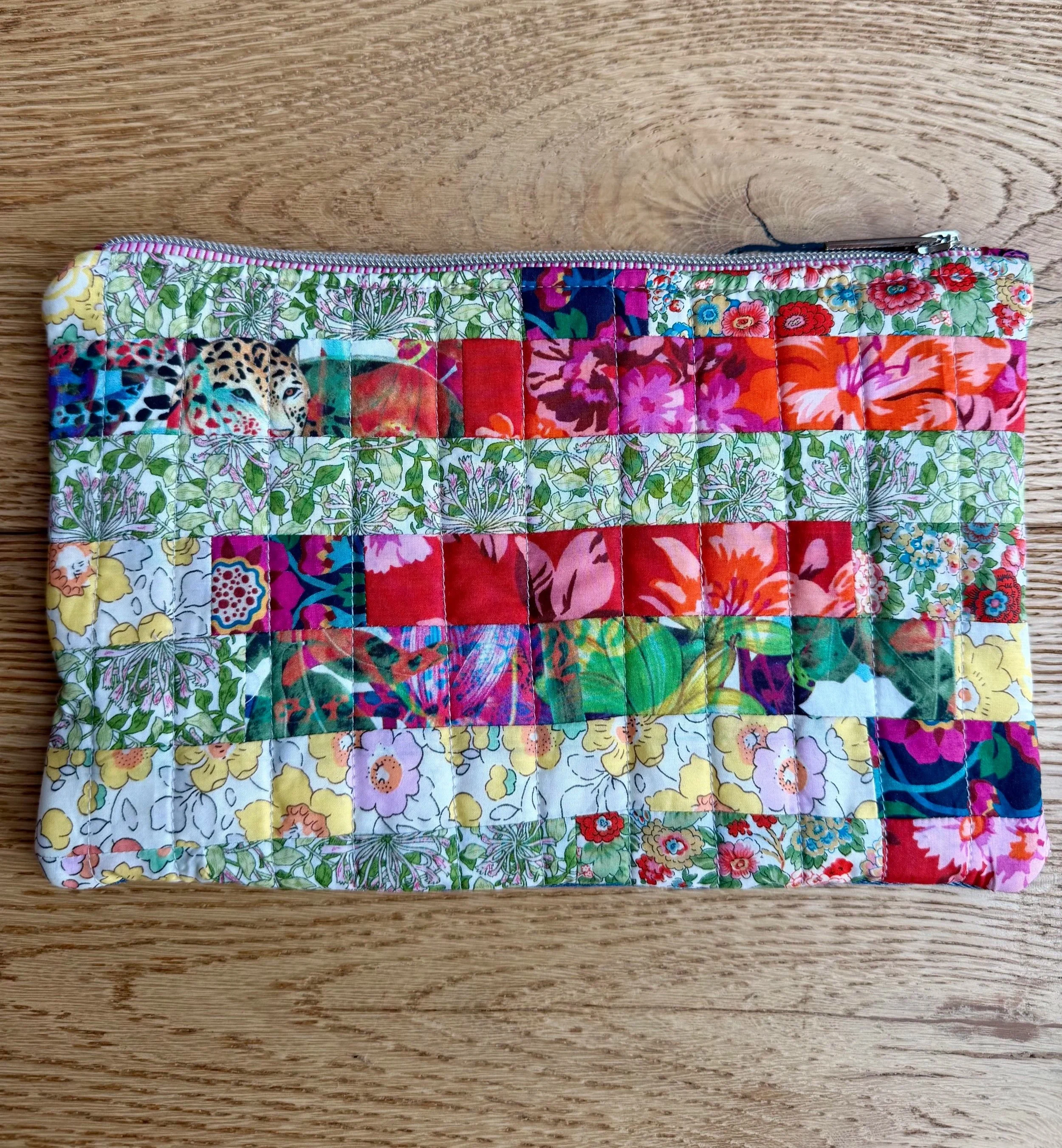 Liberty Tutti Fruitti pouch made from colourful strips of floral cotton lawn, with quilted stitching and a zip closure.