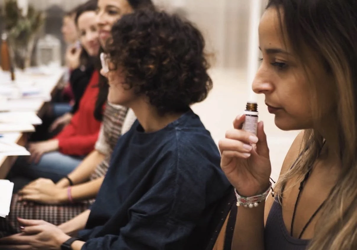 Mujer inhalando un aroma en una sala de reuniones con varias personas