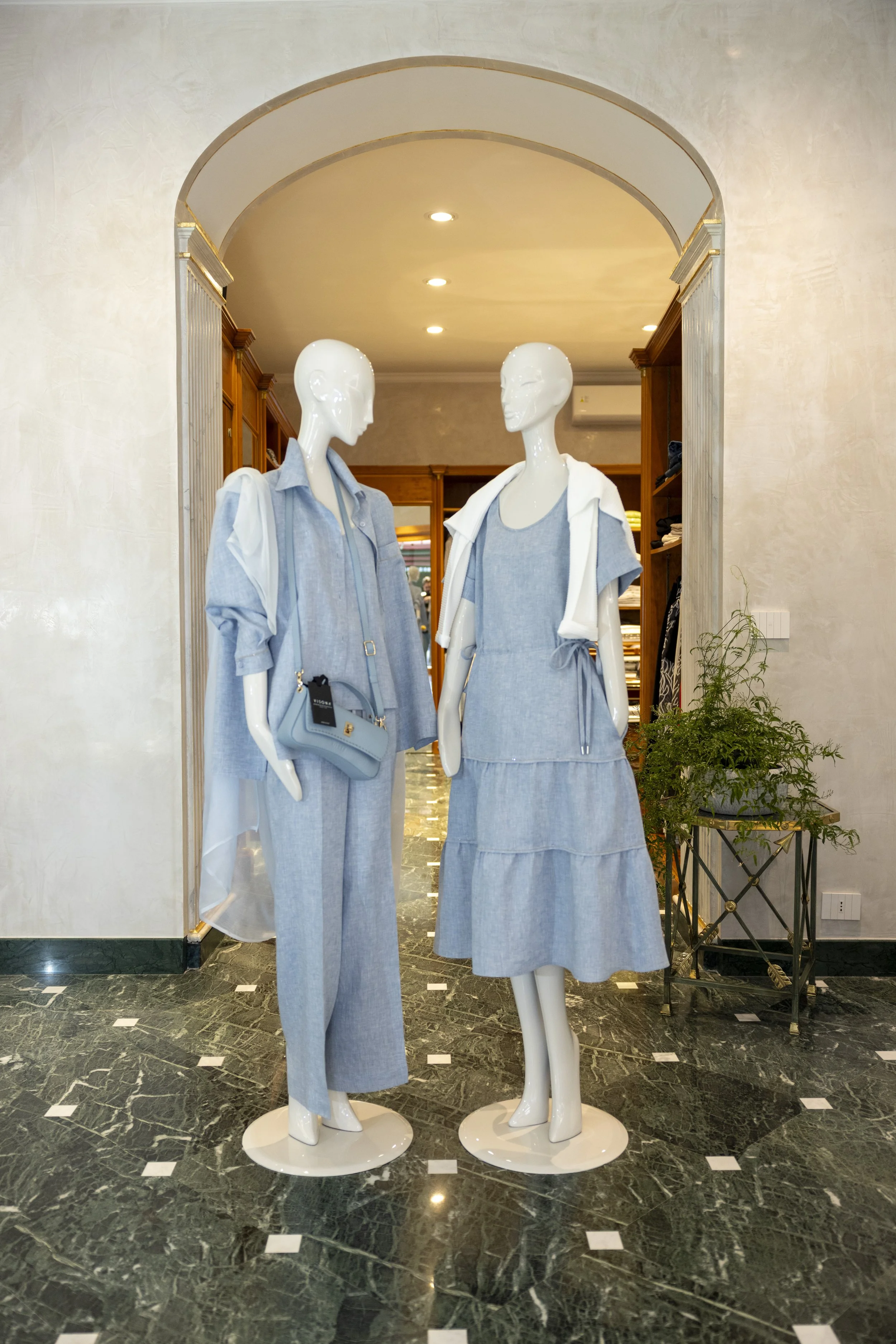 Due manichini femminili vestiti con abiti di jeans, uno con pantaloni e camicia, l'altro con gonna e top, posizionati in un negozio di abbigliamento.