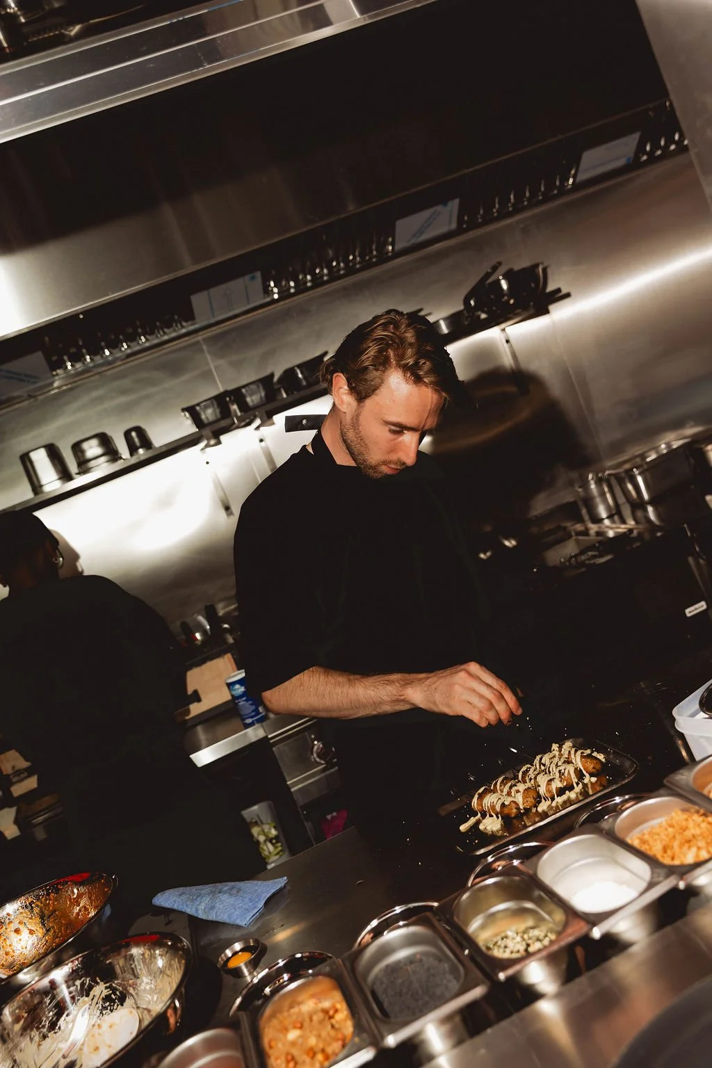A man preparing sushi in a restaurant kitchen, with various ingredients around him.