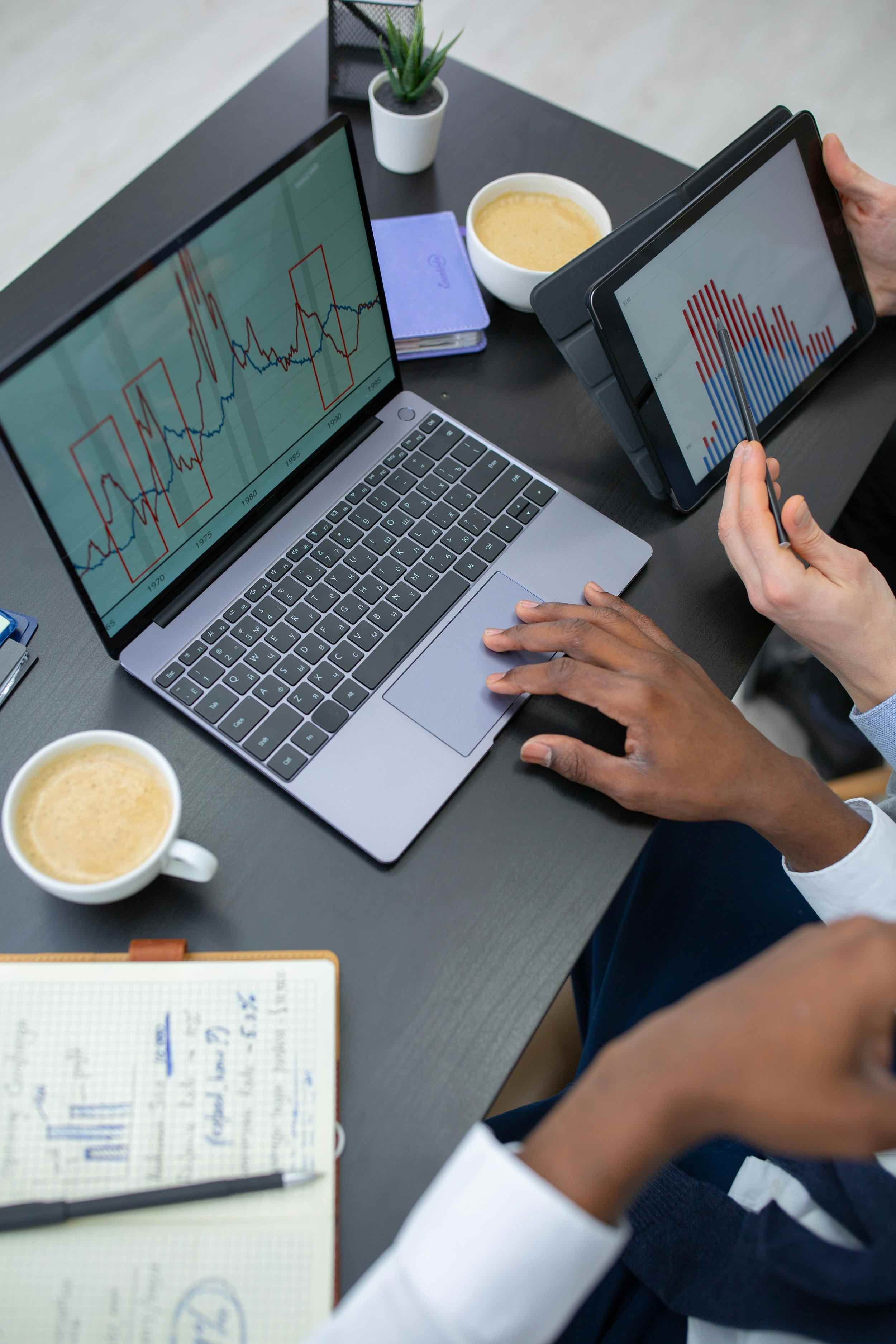 Close-up of laptop and tablet displaying financial charts, analyzing small business insurance costs and data trends.