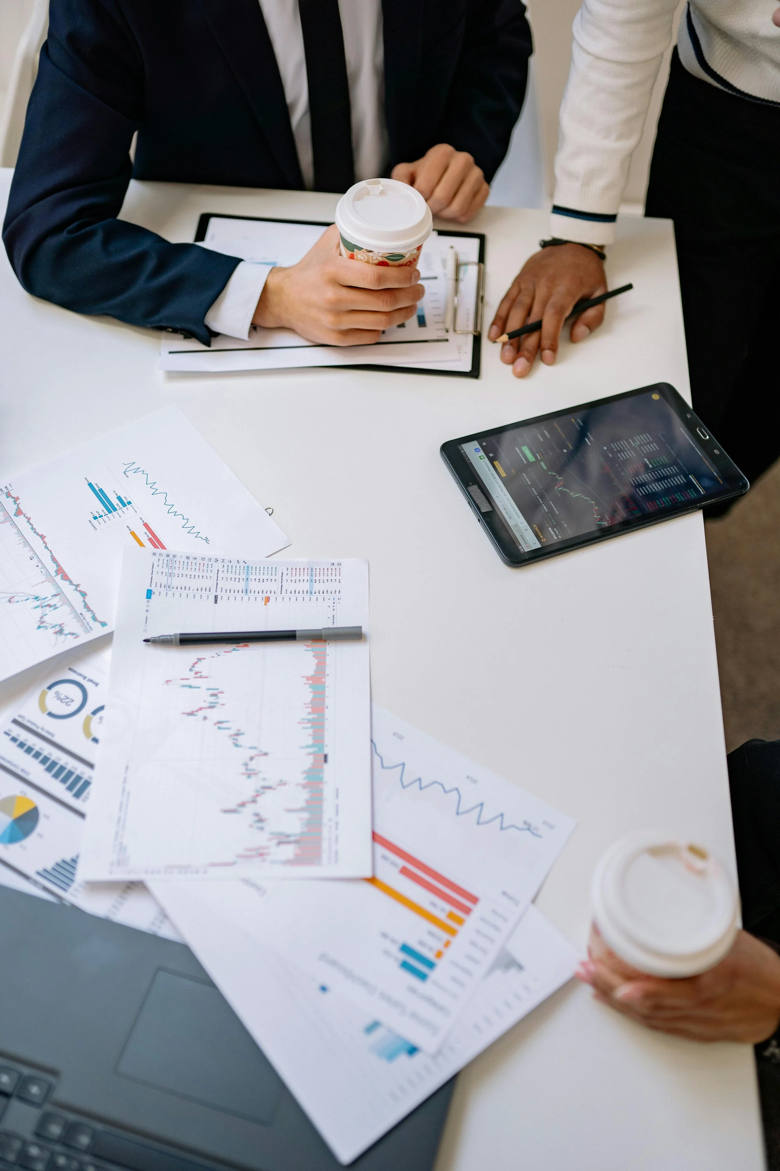 Business professionals reviewing charts and data on a desk, working with a small business insurance broker on coverage options.