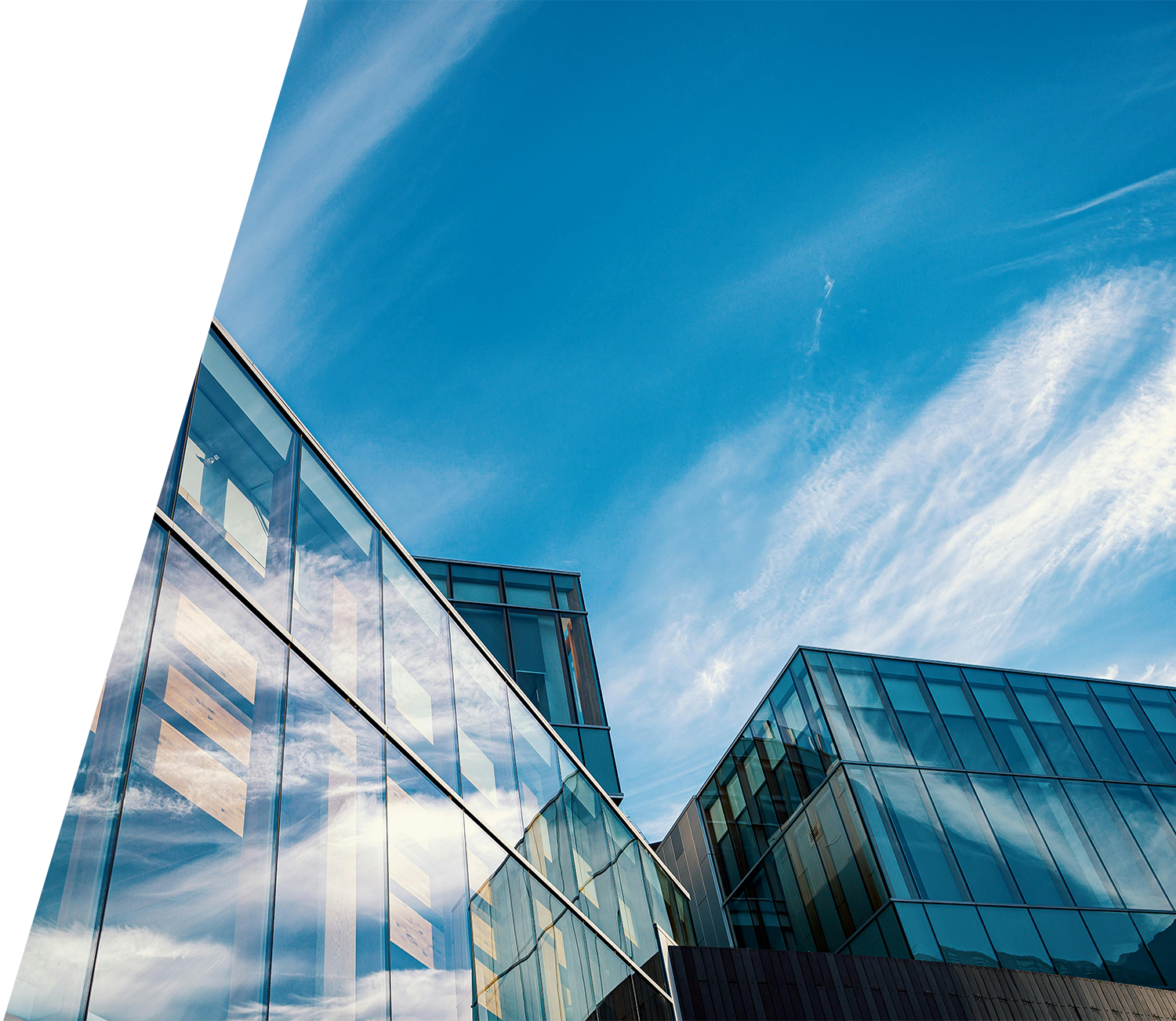 Modern glass office buildings under blue sky representing commercial insurance cost considerations for corporate properties.