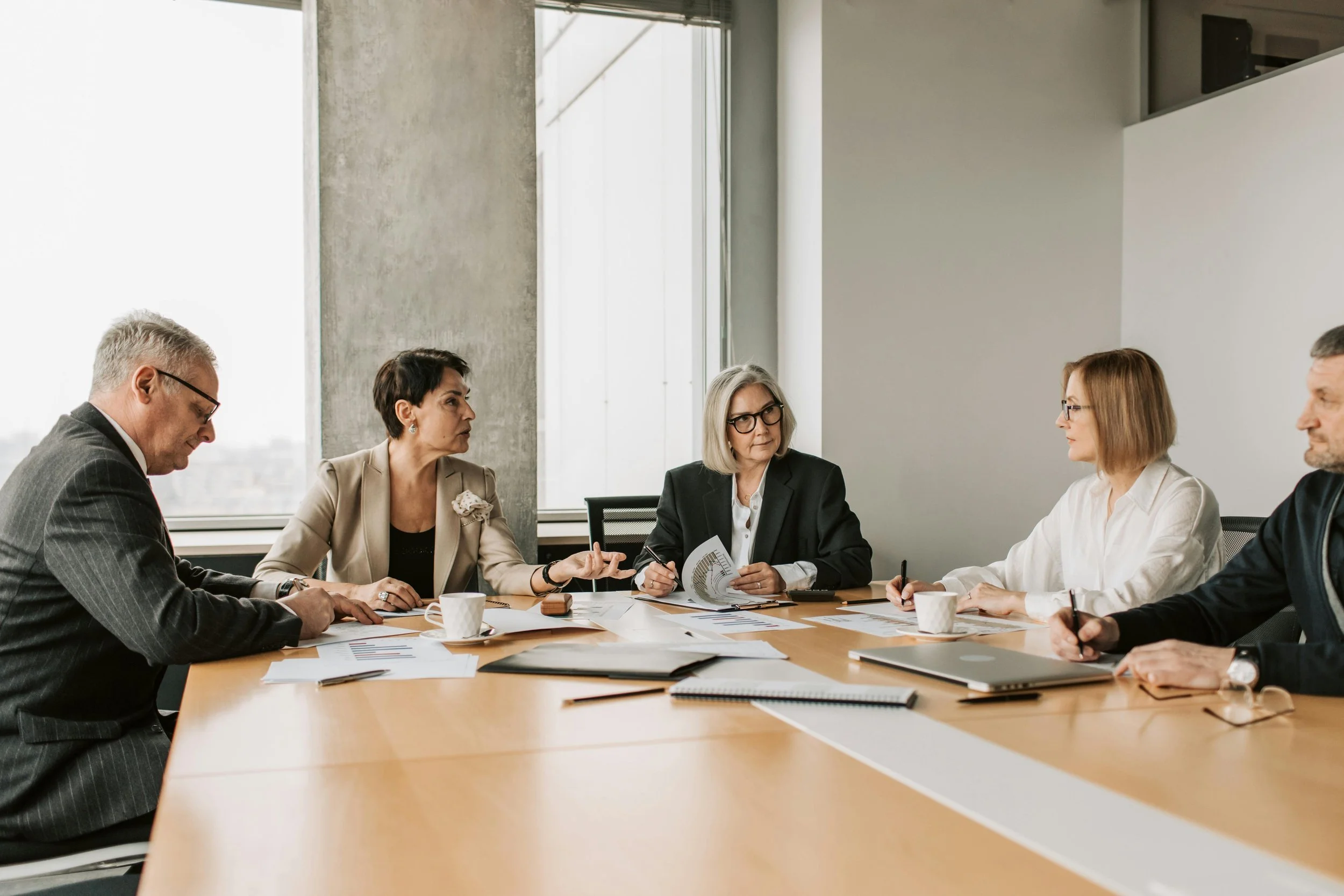 Professionals in a meeting discussing reports and strategy with an insurance broker for business risk management.