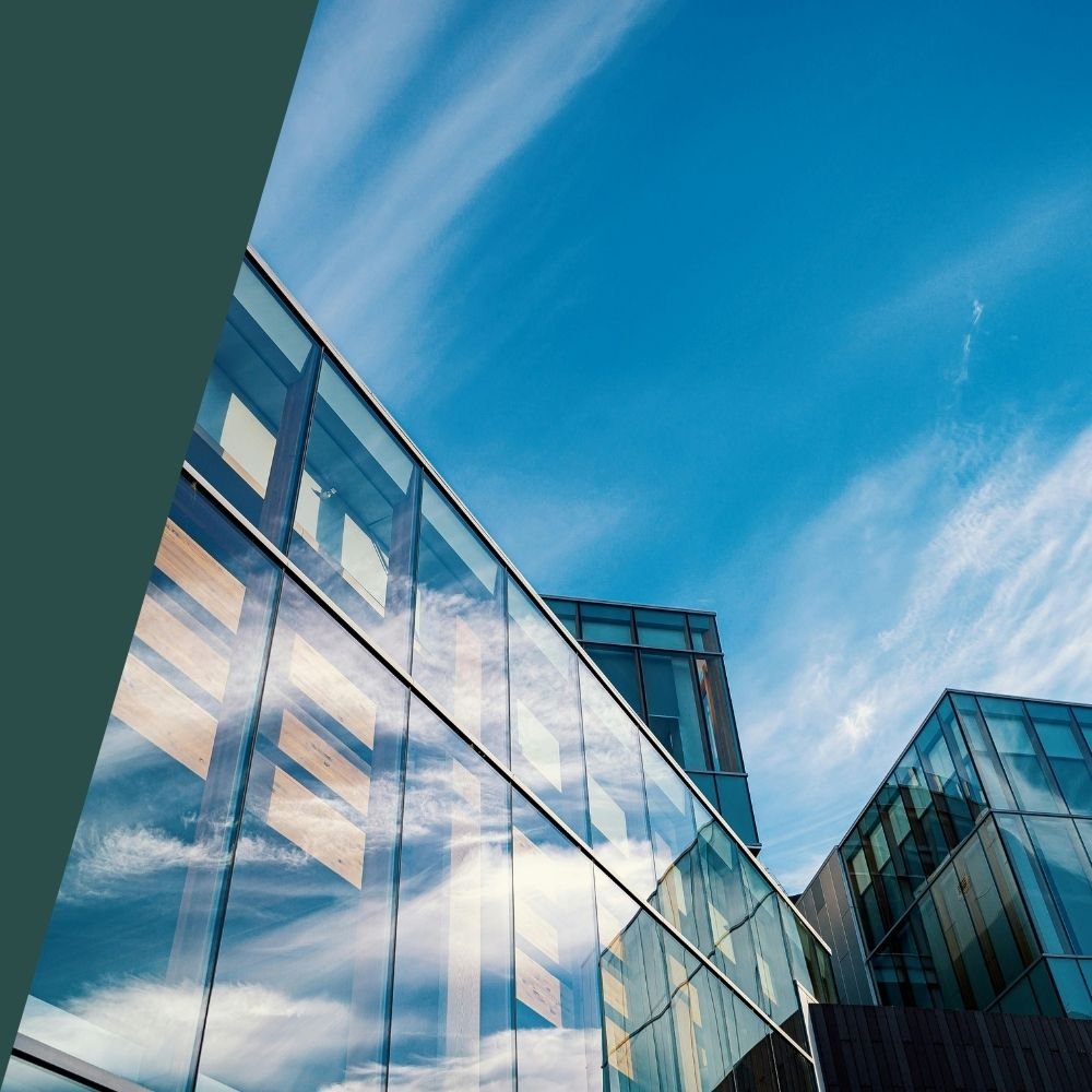 Modern glass office buildings under blue sky representing commercial insurance cost considerations for corporate properties.