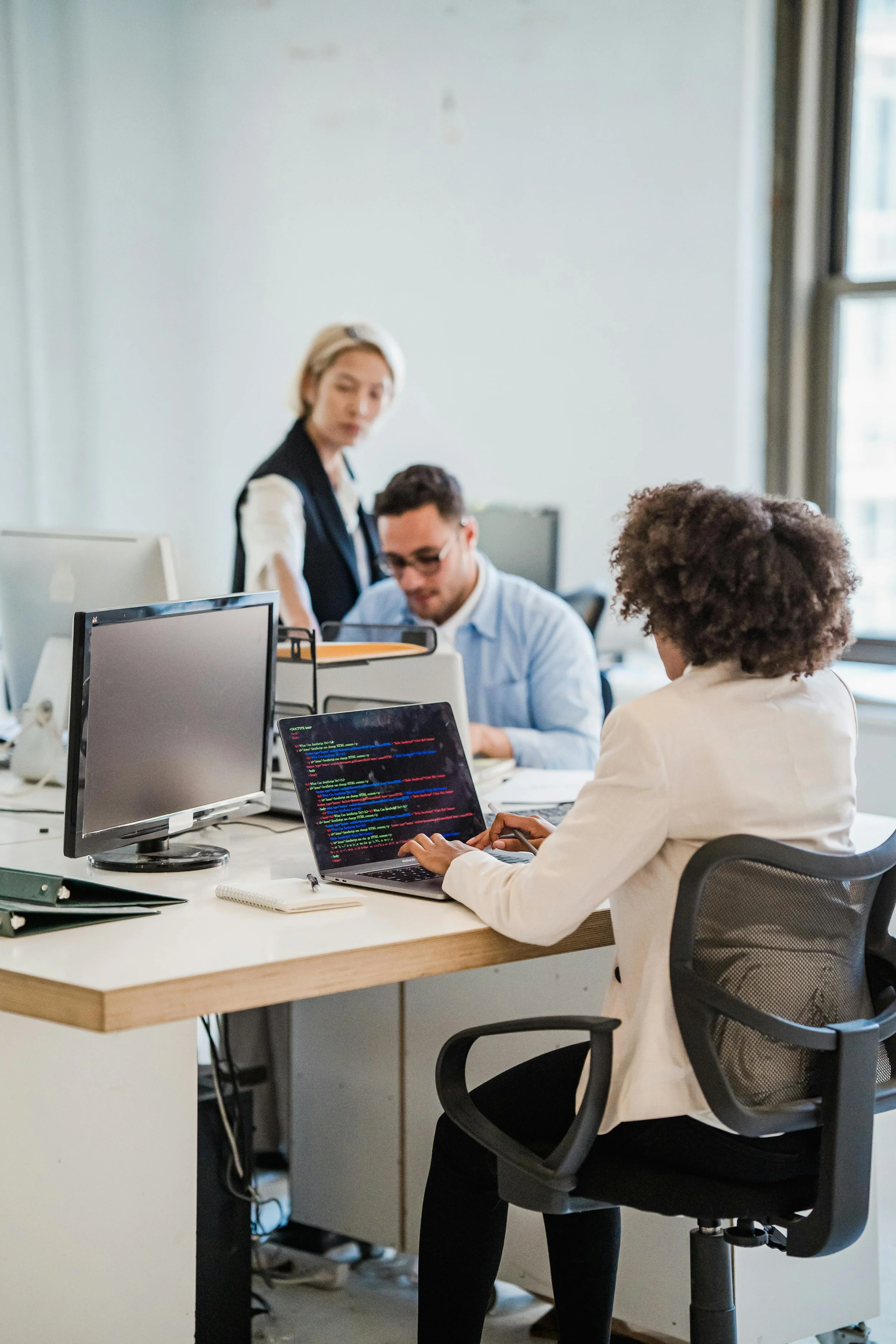 Diverse team collaborating at computers in a modern office, highlighting business insurance for small business and workplace productivity.