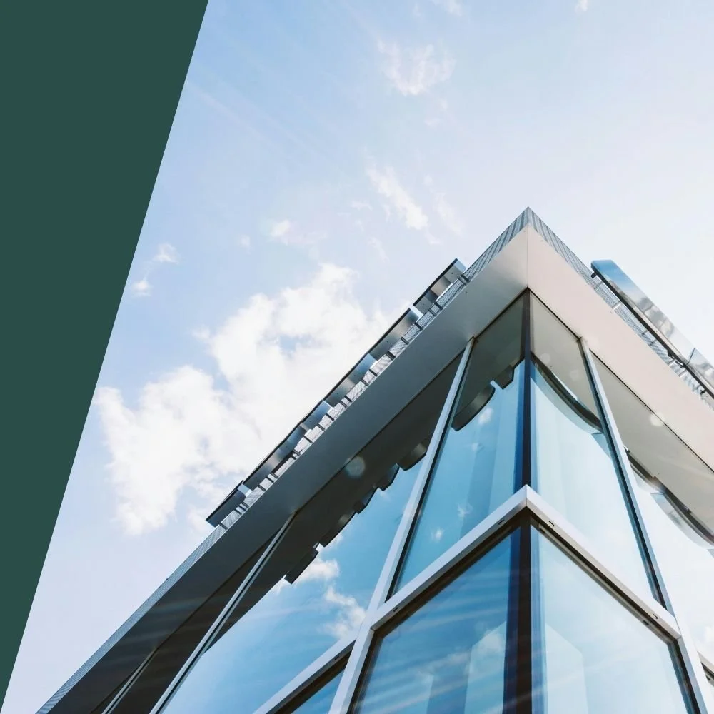 Modern glass office building under blue sky representing corporate offices of a business insurance broker.