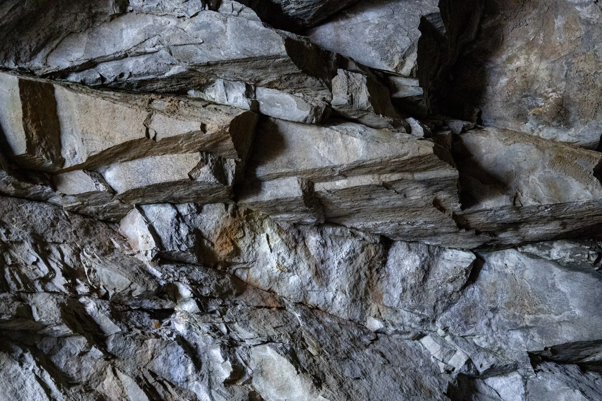 A close-up view of a rocky cave wall with irregular, layered gray and brown stones.
