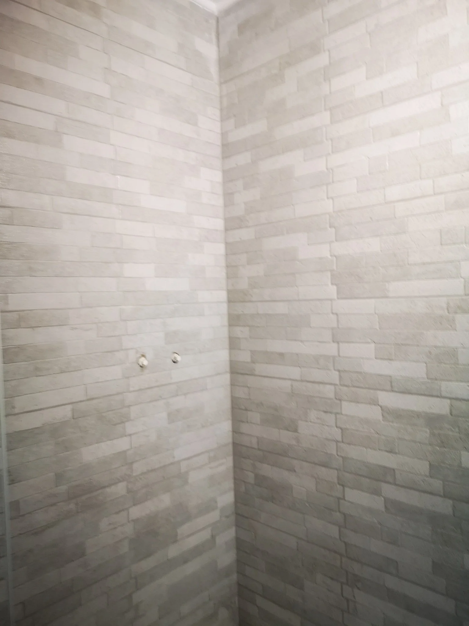 Interior of a room with white brick walls and two small holes near the corner.