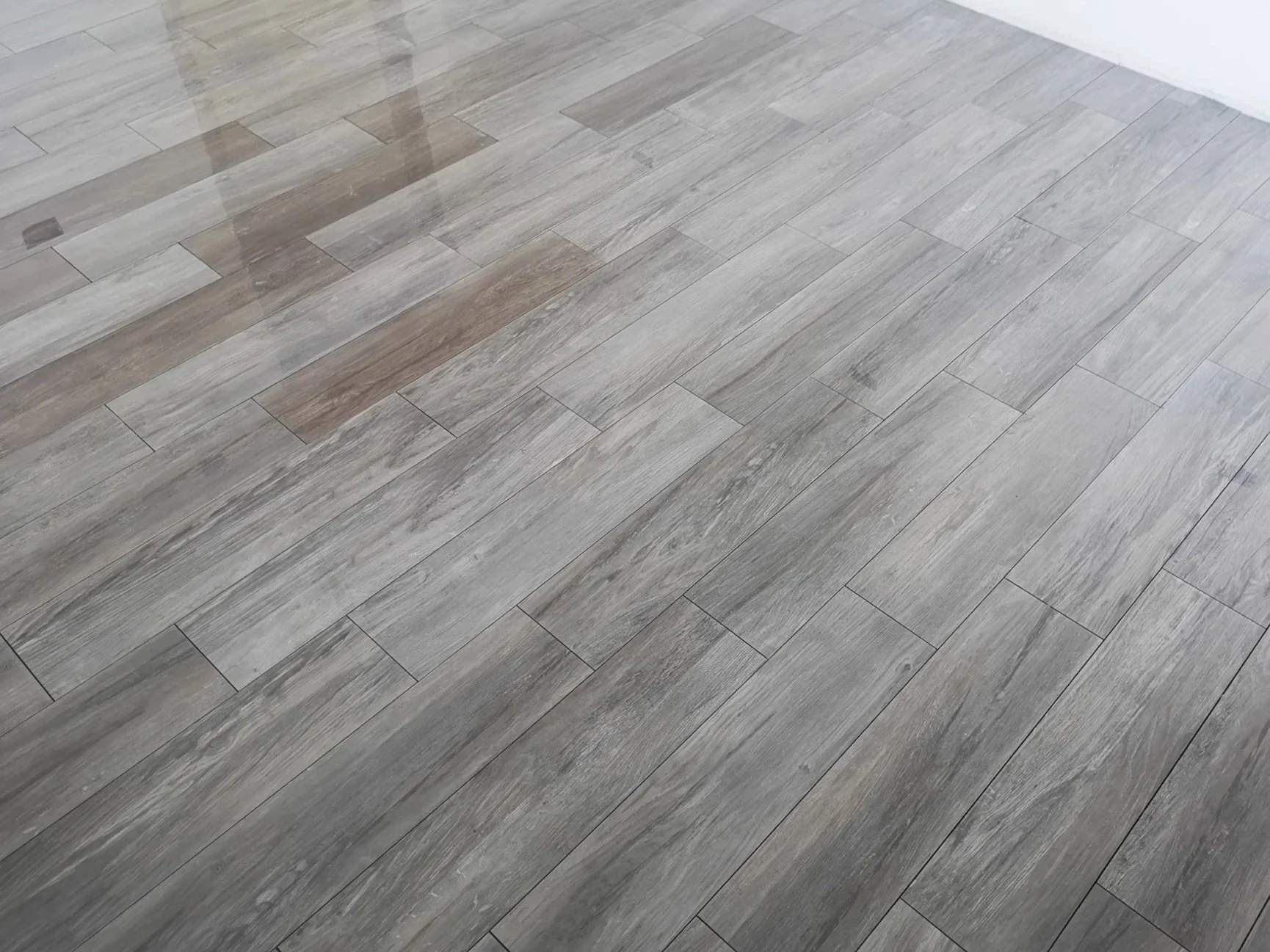 Gray wood-textured floor with a section of brownish wood-textured tiles near the top left corner.