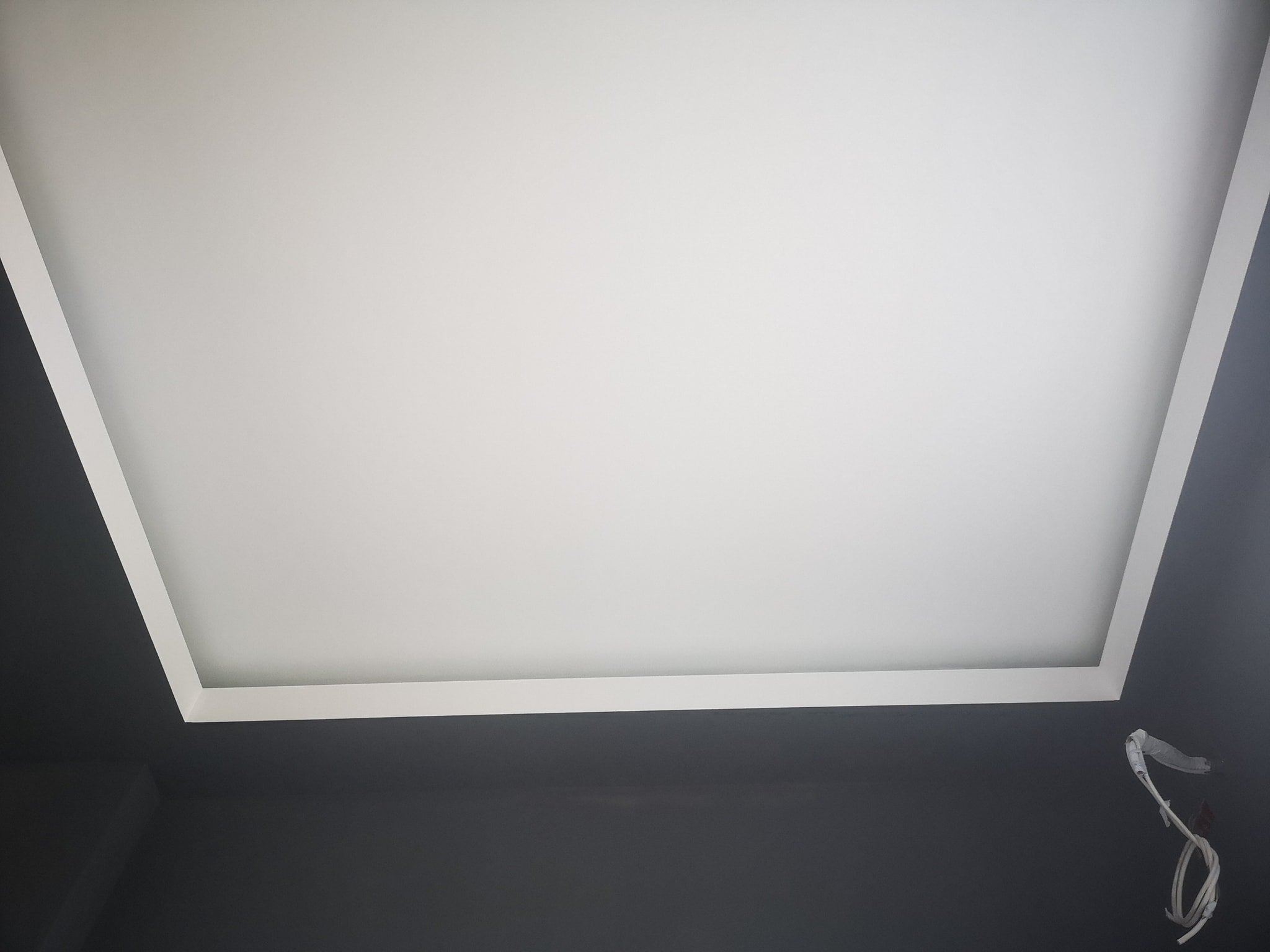Ceiling with a rectangular recessed area surrounded by white molding, black walls, and a white cord hanging from the corner.