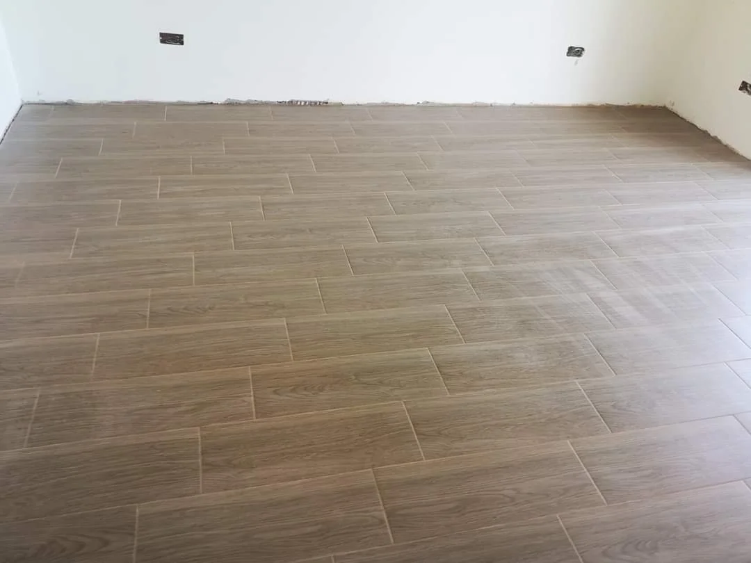 Empty room with wood-look tile flooring and unfinished walls with electrical outlets.