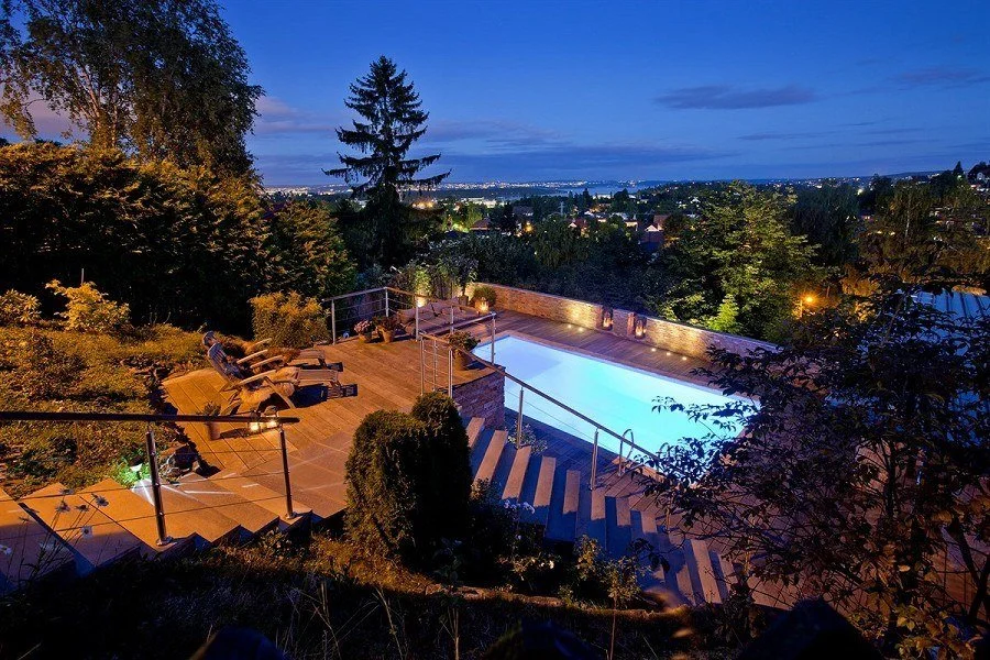 Opplyst basseng og terrasse i Thermo-ask med utsikt over Oslofjorden om kvelden