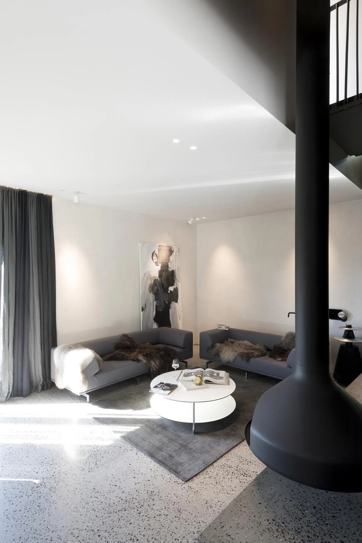 Stue i tilbygget med grå sofaer, saueskinn og stor abstrakt kunst