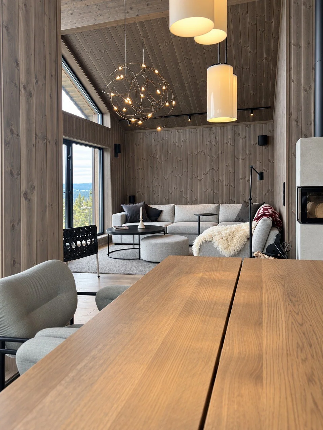 Stue med høyt himlingsløft, lys sofa og peis, sett fra spisebordet, Varden Panorama Kvitfjell