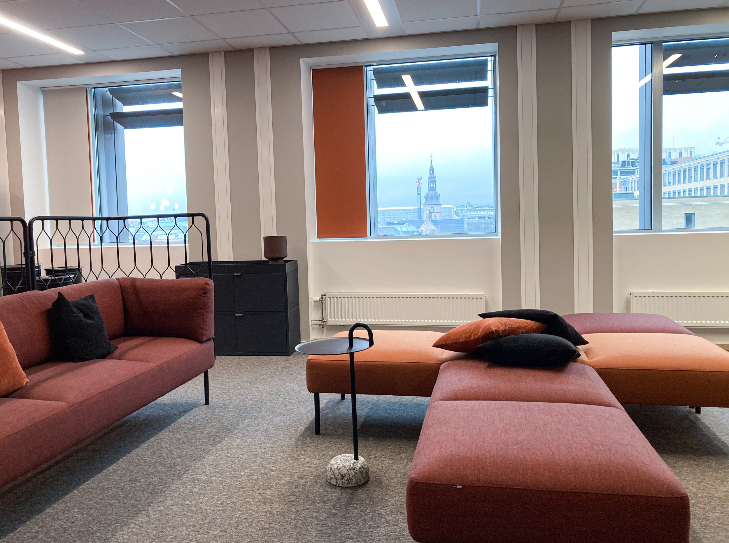 Sosial sone med sofaer i rustfarger og utsikt mot Oslo domkirke, Spordrift