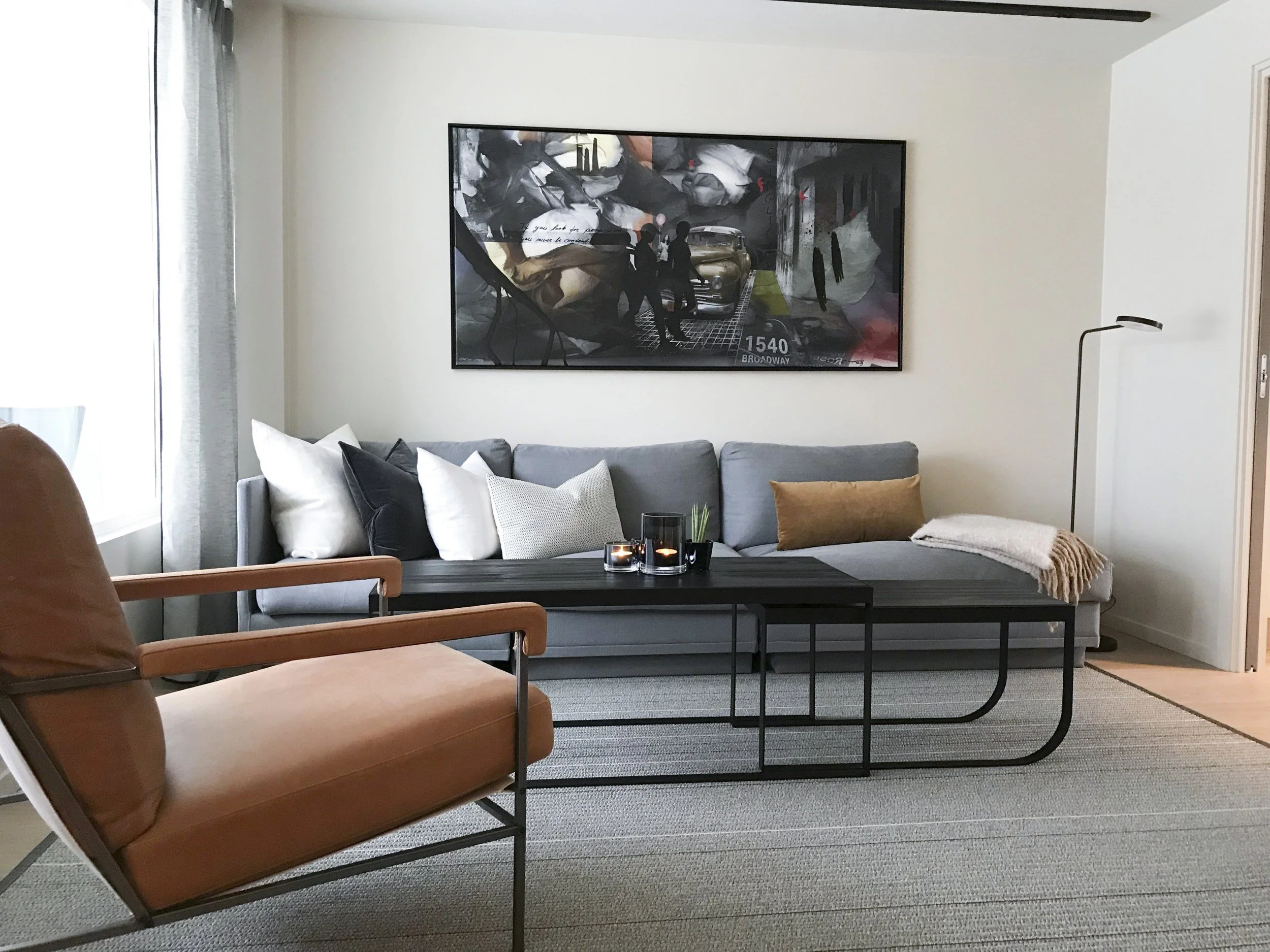 Stue med grå sofa, sort sofabord, lenestol i cognac skinn og stort kunstverk, Tonsenhagen